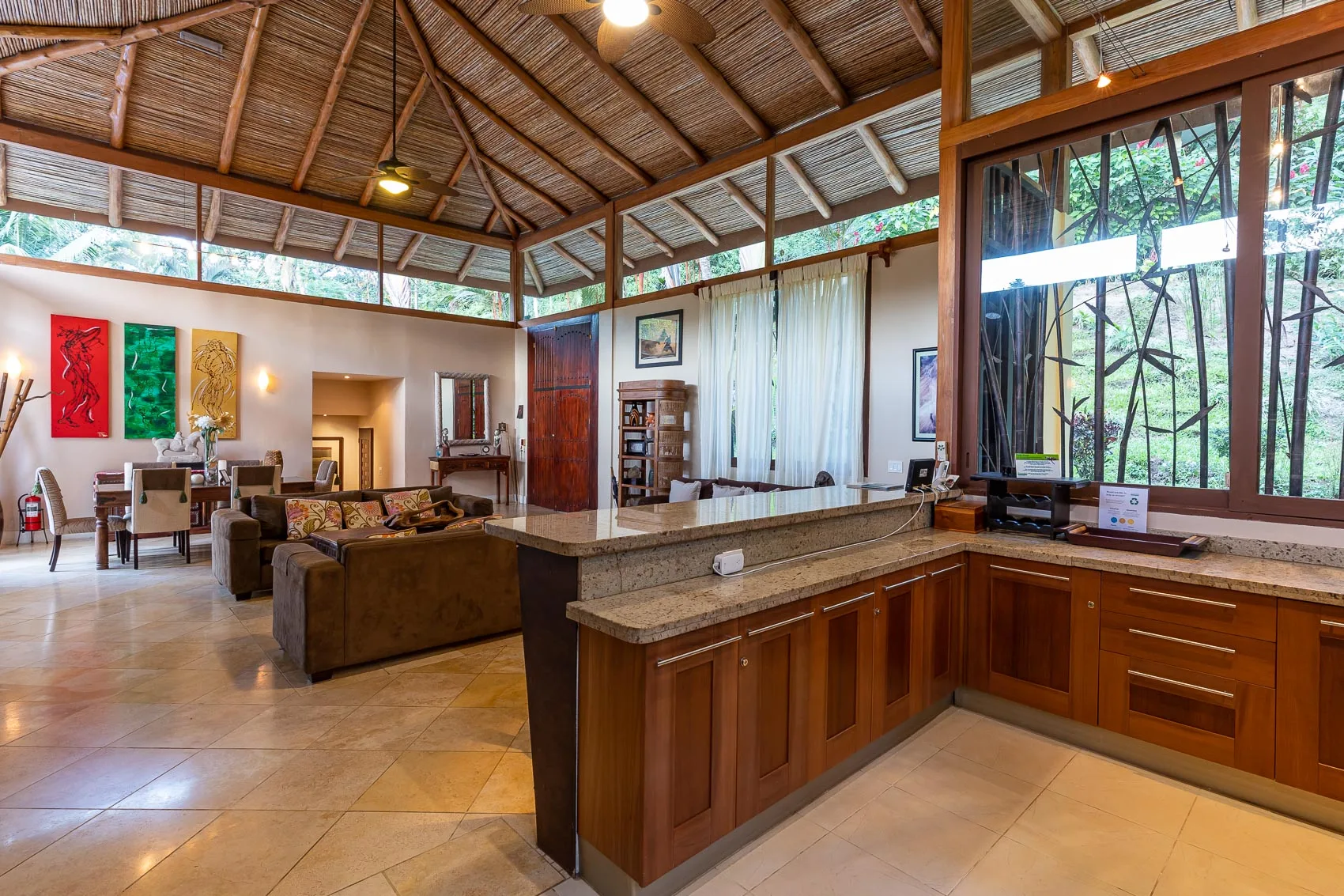 Sala de estar diáfana con mesa de comedor e isla de cocina bajo un techo alto de madera.