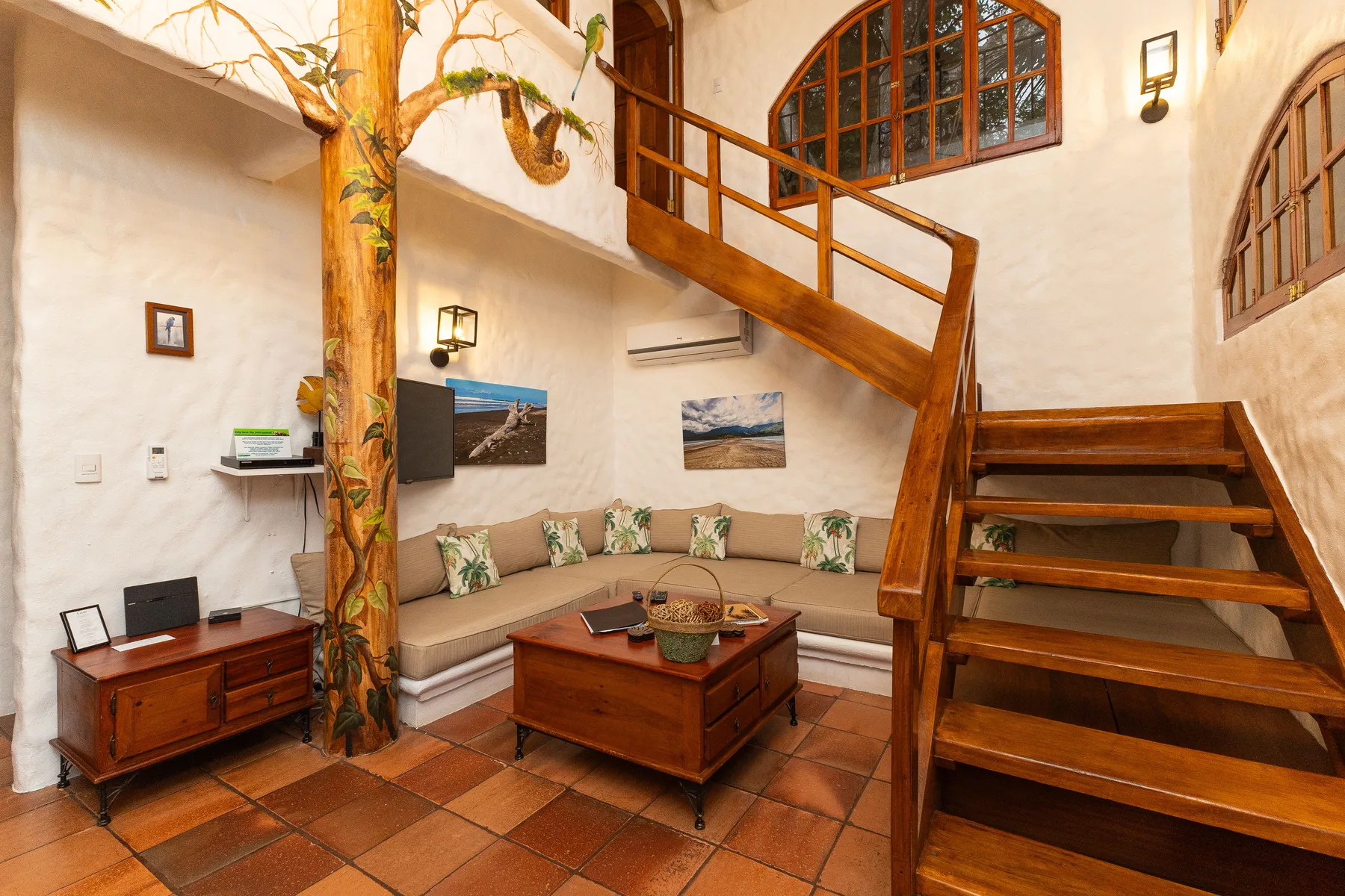 A living room with a corner seating area, wooden coffee table, and staircase.