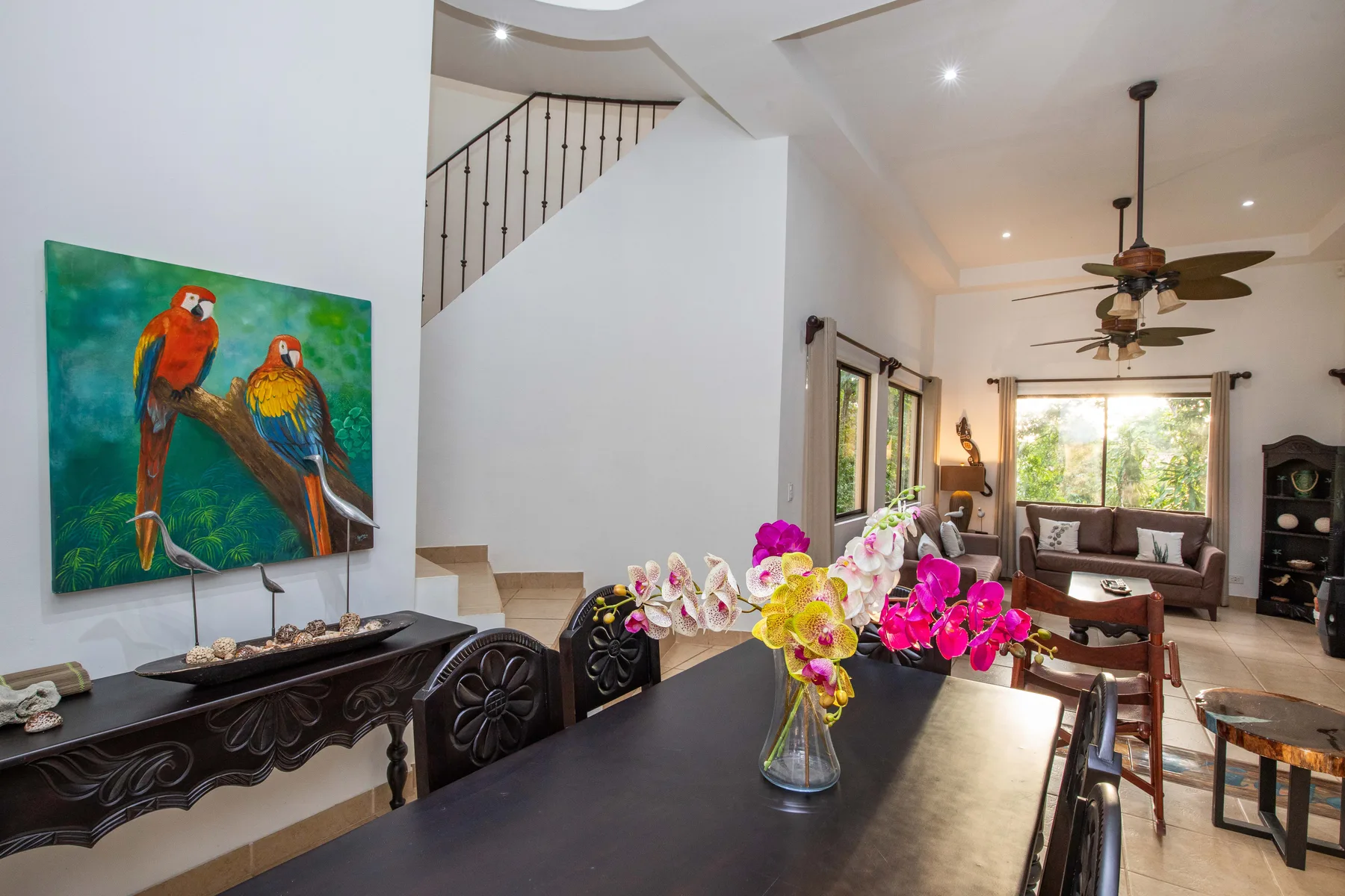 An open dining and living area with colorful flowers on the dining table.