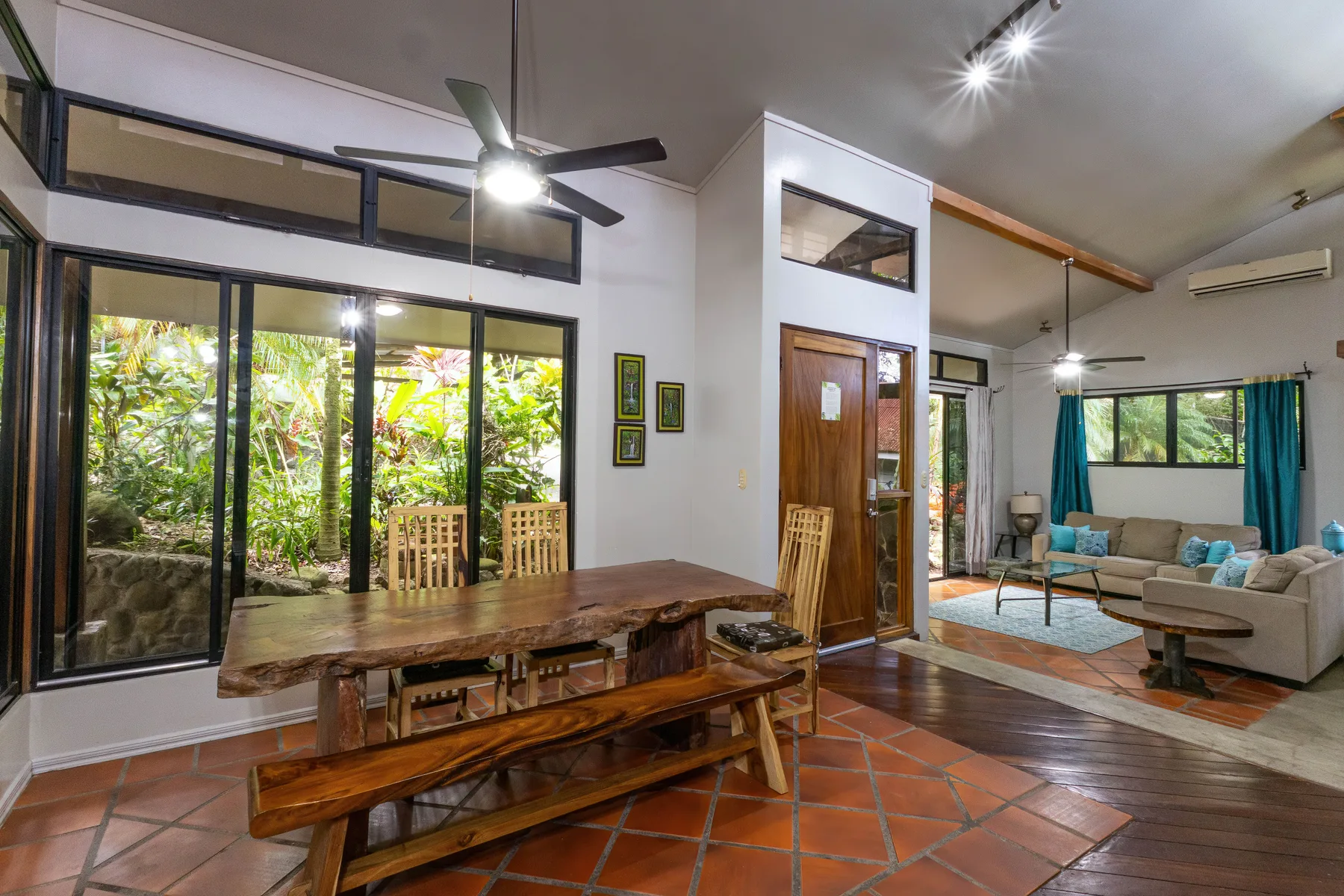 Una sala de estar y comedor diáfana con una mesa de madera y asientos.
