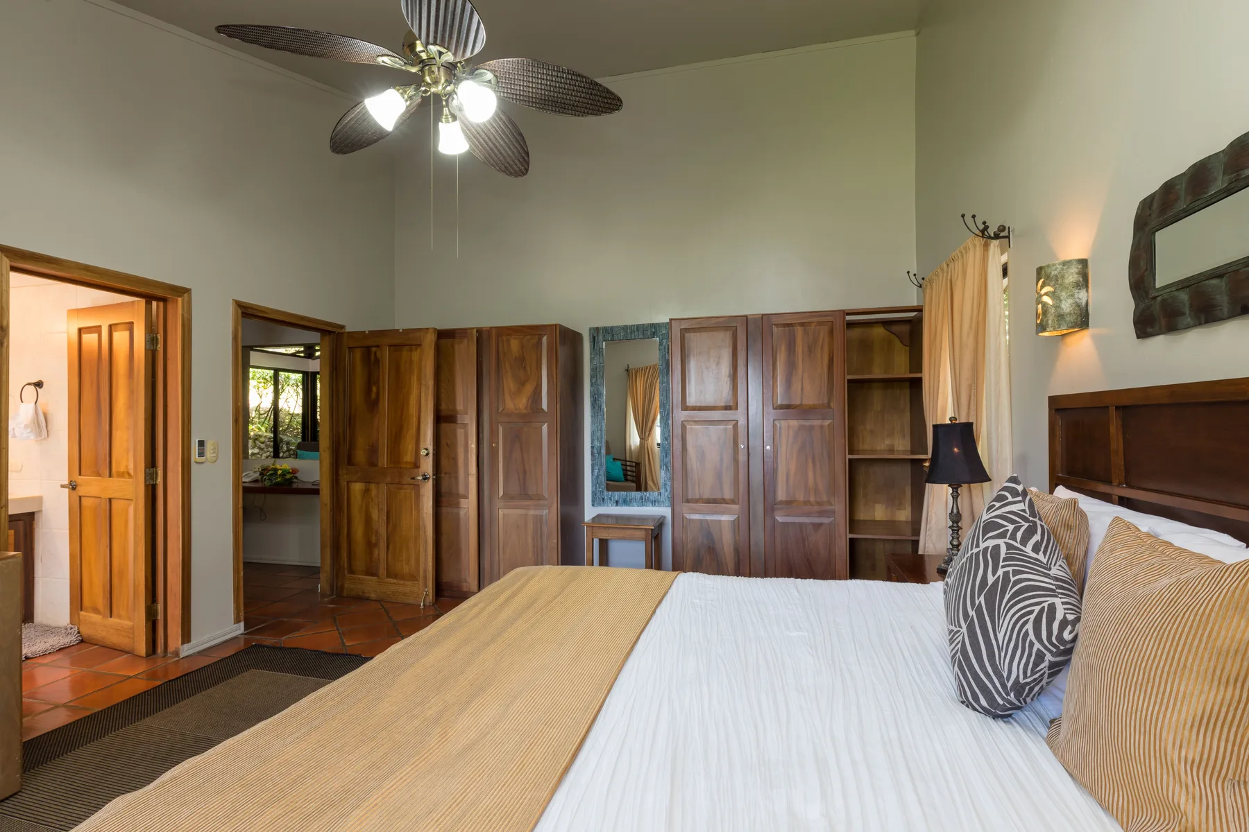 Un dormitorio con una cama bien arreglada y armarios de madera junto a la pared.