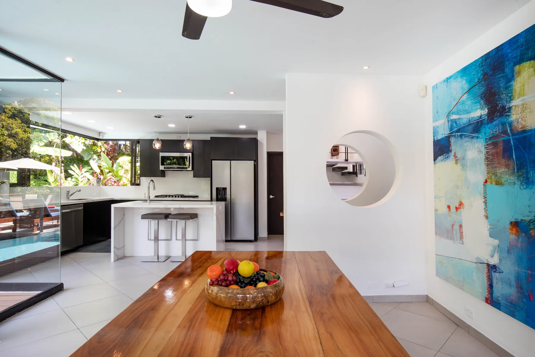 Un comedor de planta abierta y cocina, con una mesa de madera y arte colorido en la pared.