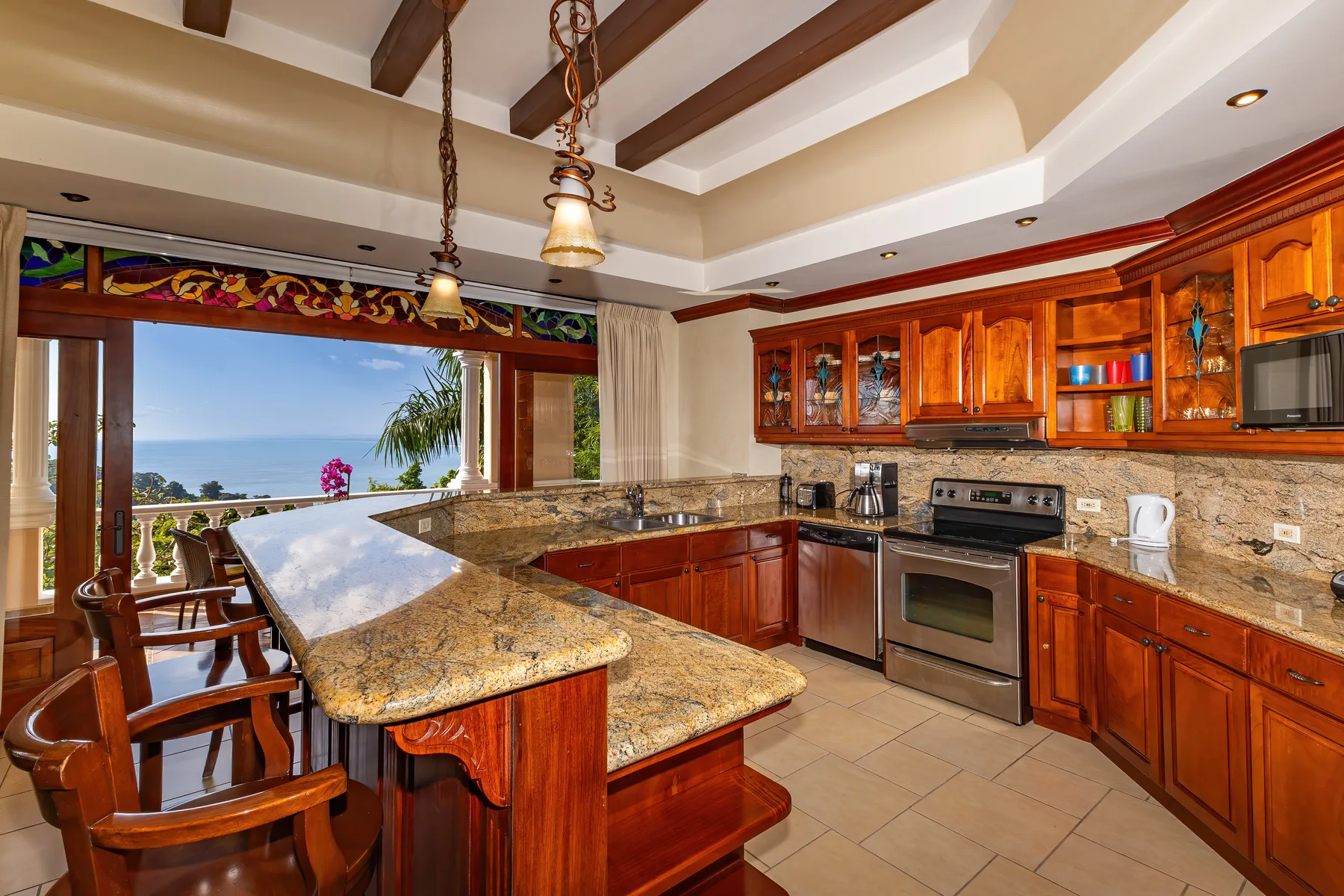 A kitchen with wooden cabinetry, a central island, and a large window overlooking the outdoors.