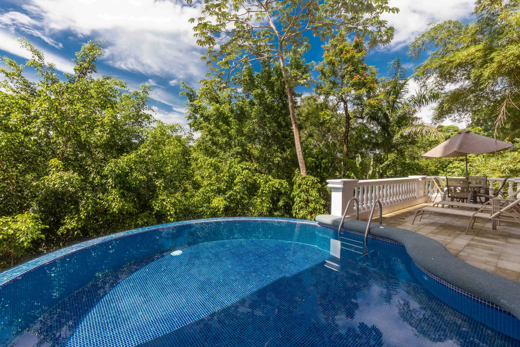 Shared amenity: An outdoor swimming pool beside a patio with seating and an umbrella.