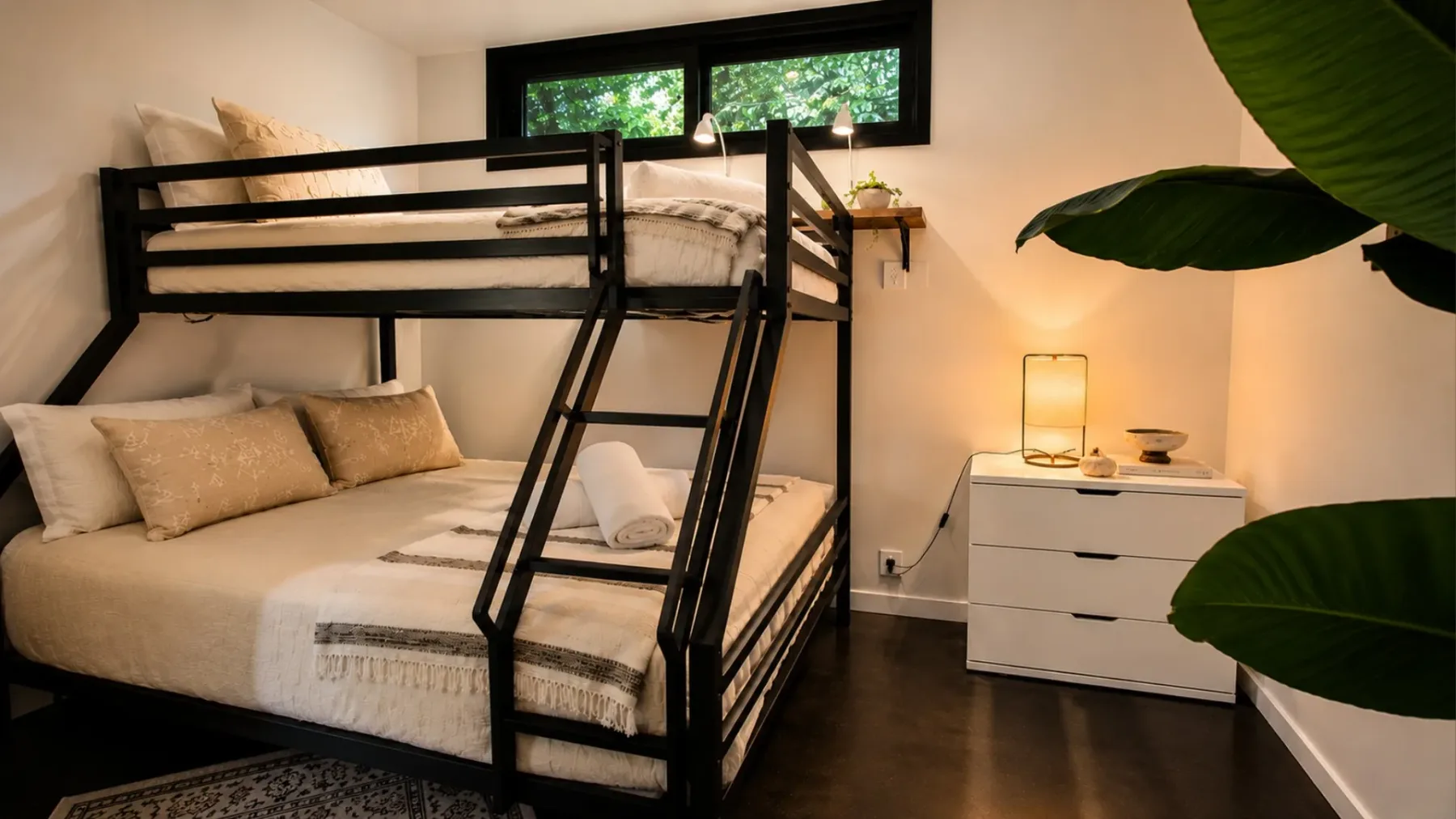 A bedroom with a black bunk bed, white bedding, and a small dresser.