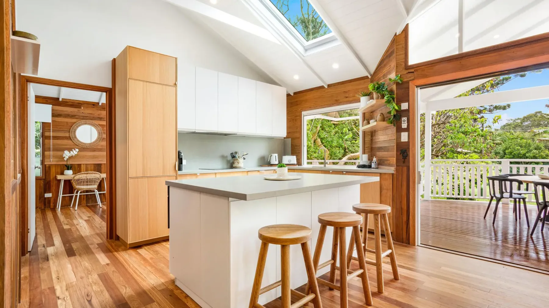 Una cocina luminosa con una isla central y grandes ventanas que dan a una terraza.