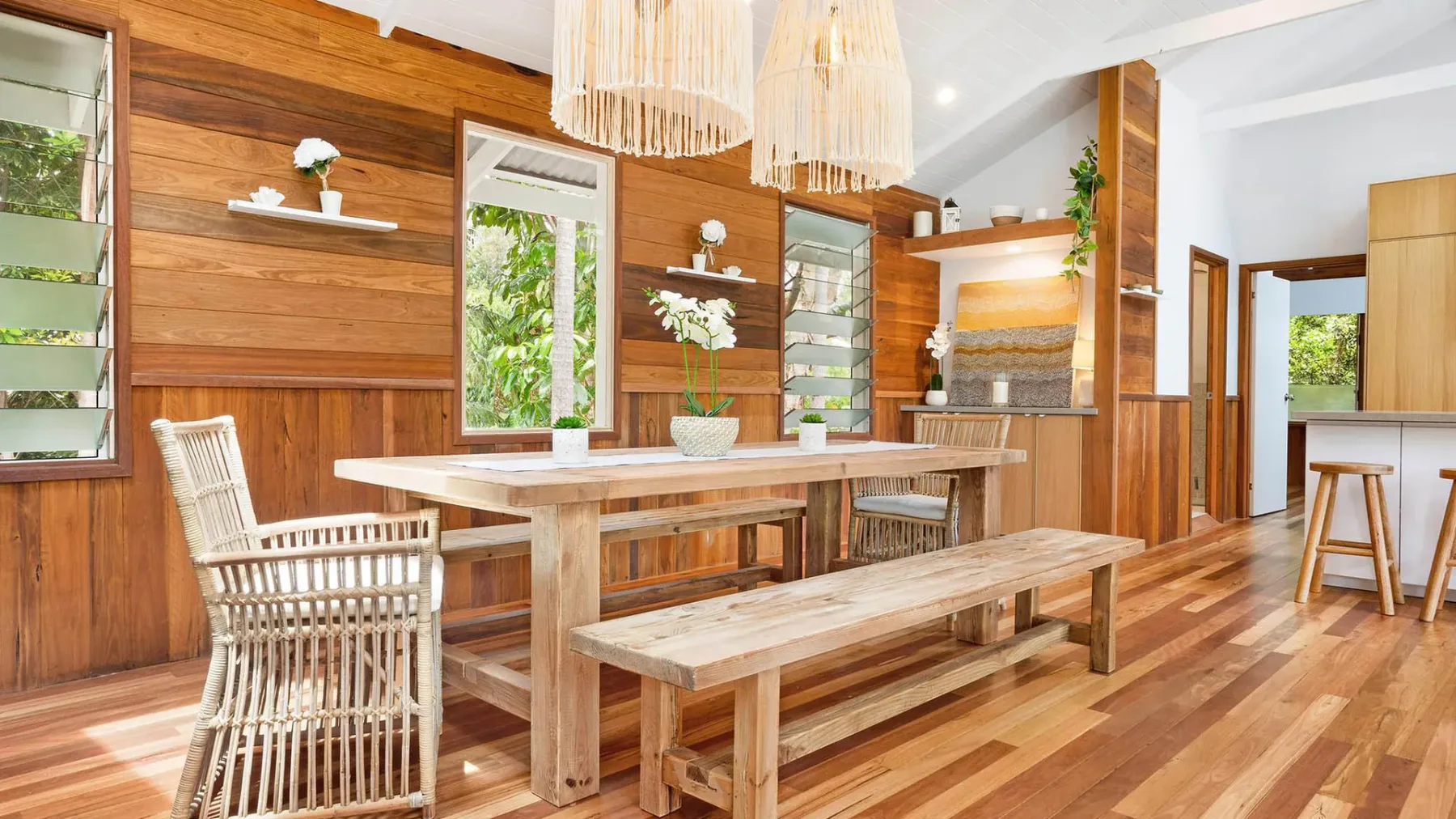 Comedor con paredes revestidas de madera, mesa larga y bancos.