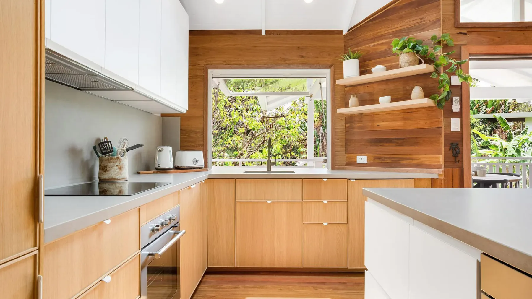 Una cocina luminosa con gabinetes de madera y una ventana con vista al verde.