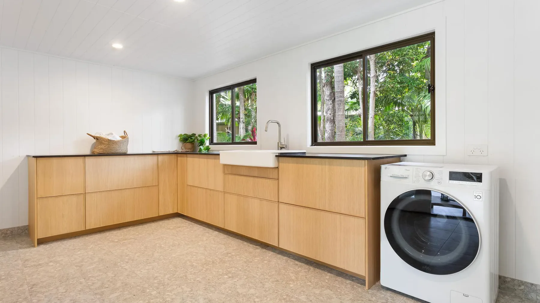 Una cocina luminosa con gabinetes de madera clara, un fregadero y una lavadora de carga frontal.