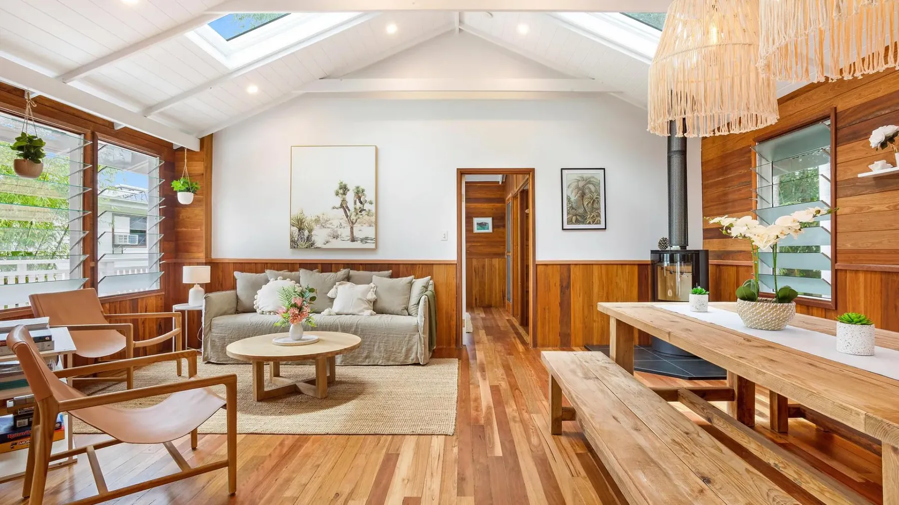 Una luminosa sala de estar y comedor revestida de madera, con asientos y una mesa larga.