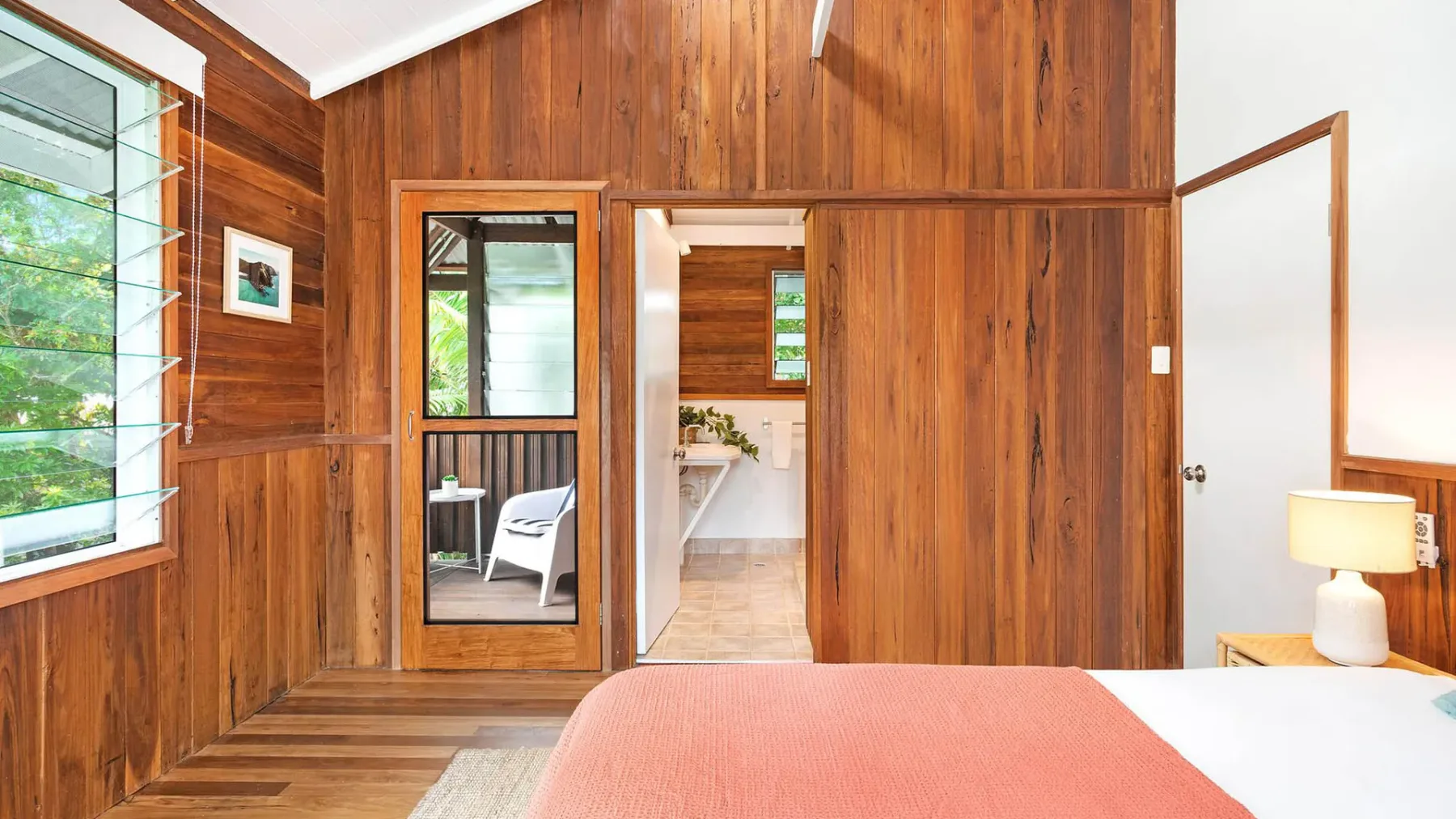 Un dormitorio con paredes revestidas de madera y una cama junto a una puerta abierta.