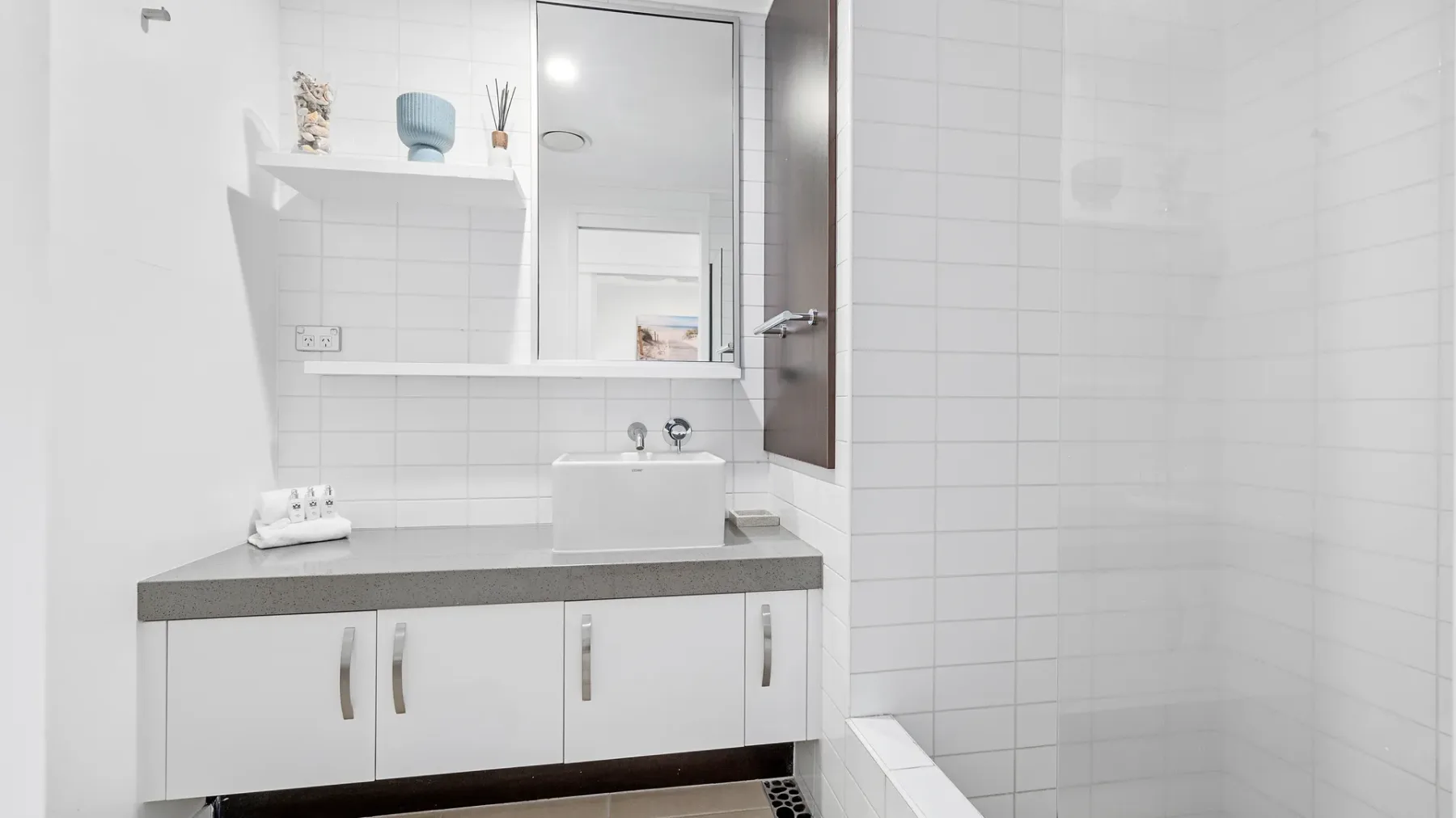 Un baño luminoso con azulejos, un mueble blanco, lavabo y espejo.