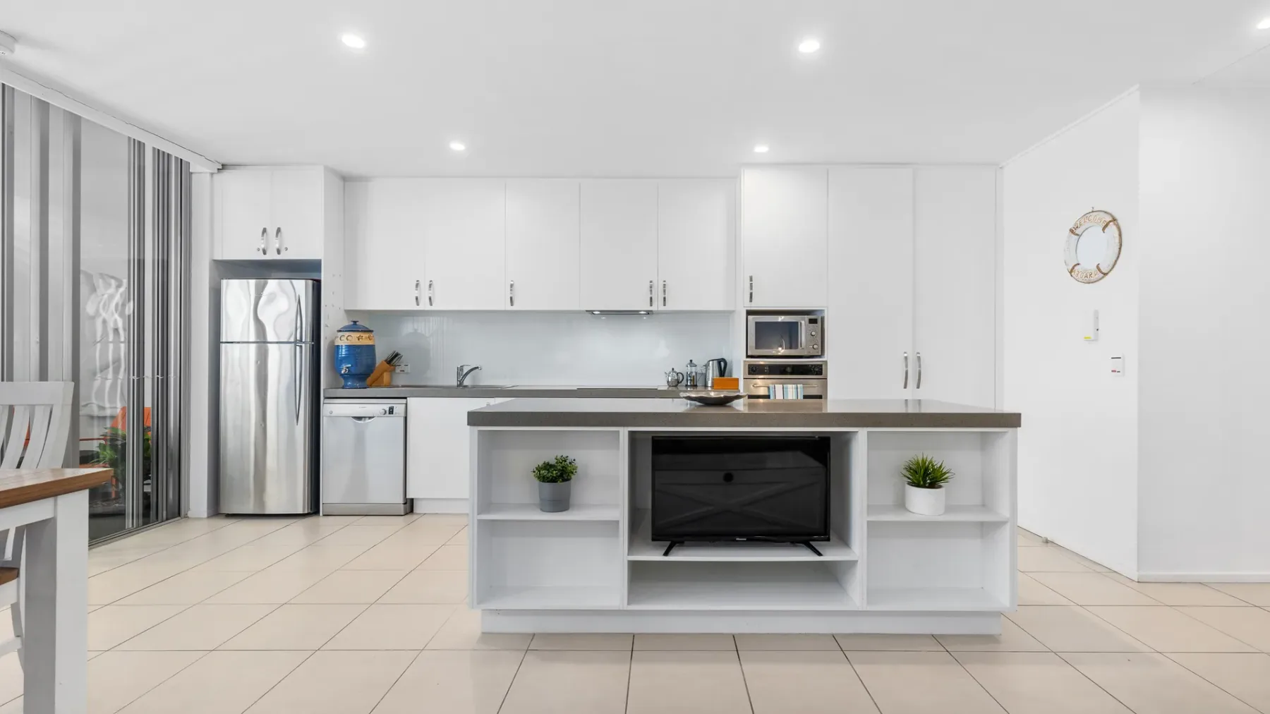 Una cocina luminosa con gabinetes blancos y una isla central.