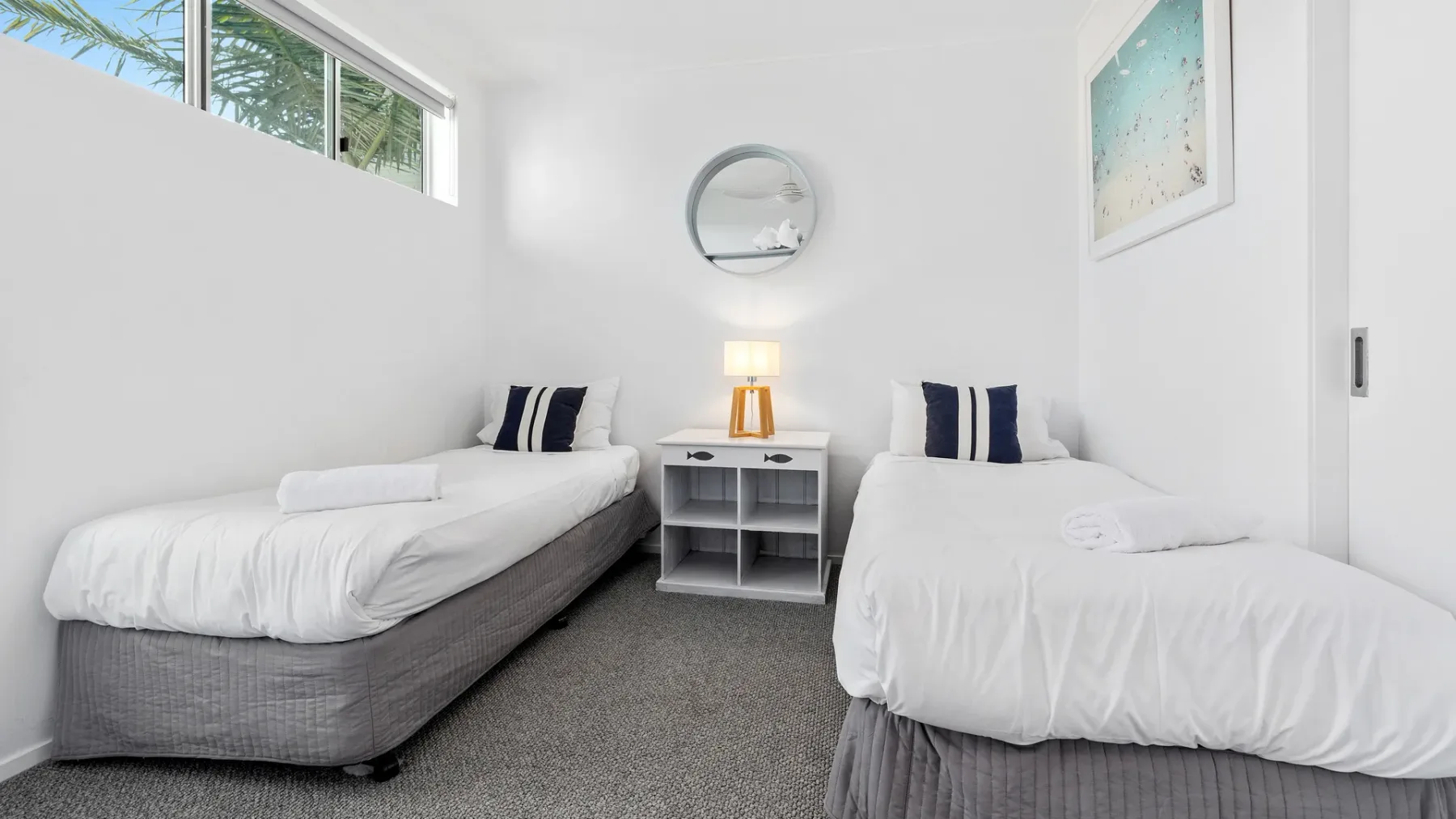 Un dormitorio luminoso con dos camas individuales y una mesita de noche entre ellas.