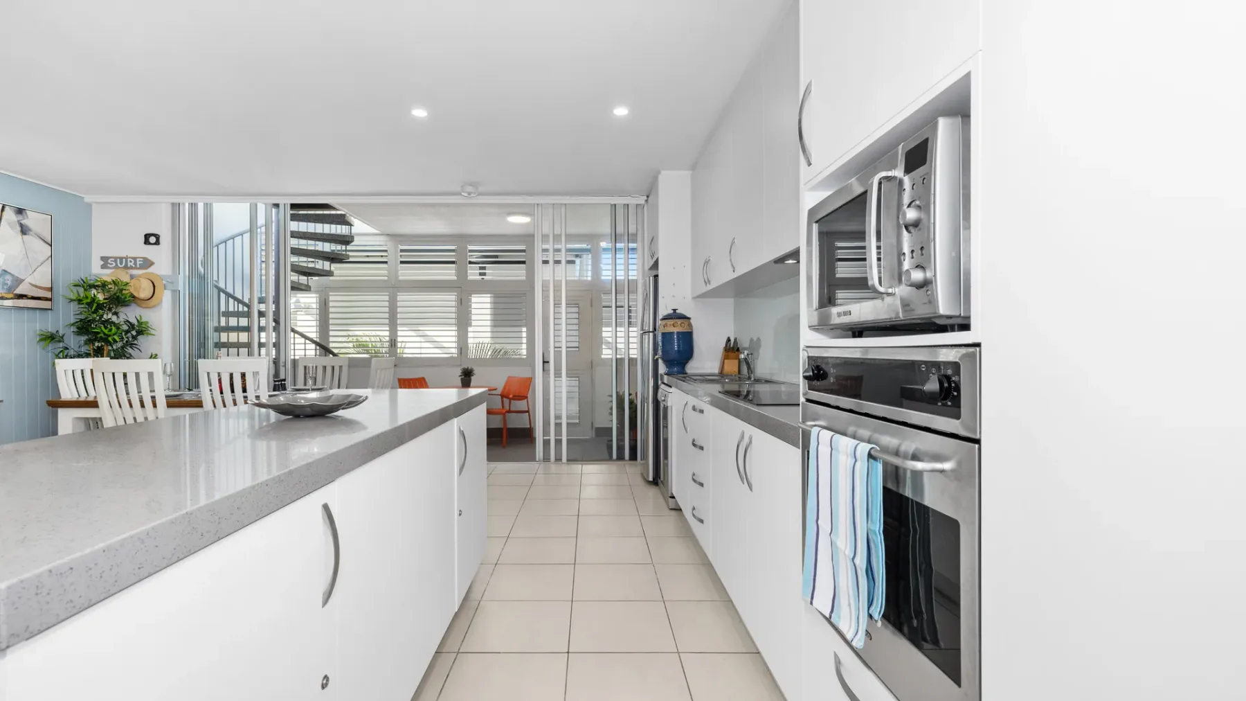 Una cocina luminosa con gabinetes blancos y una isla larga.