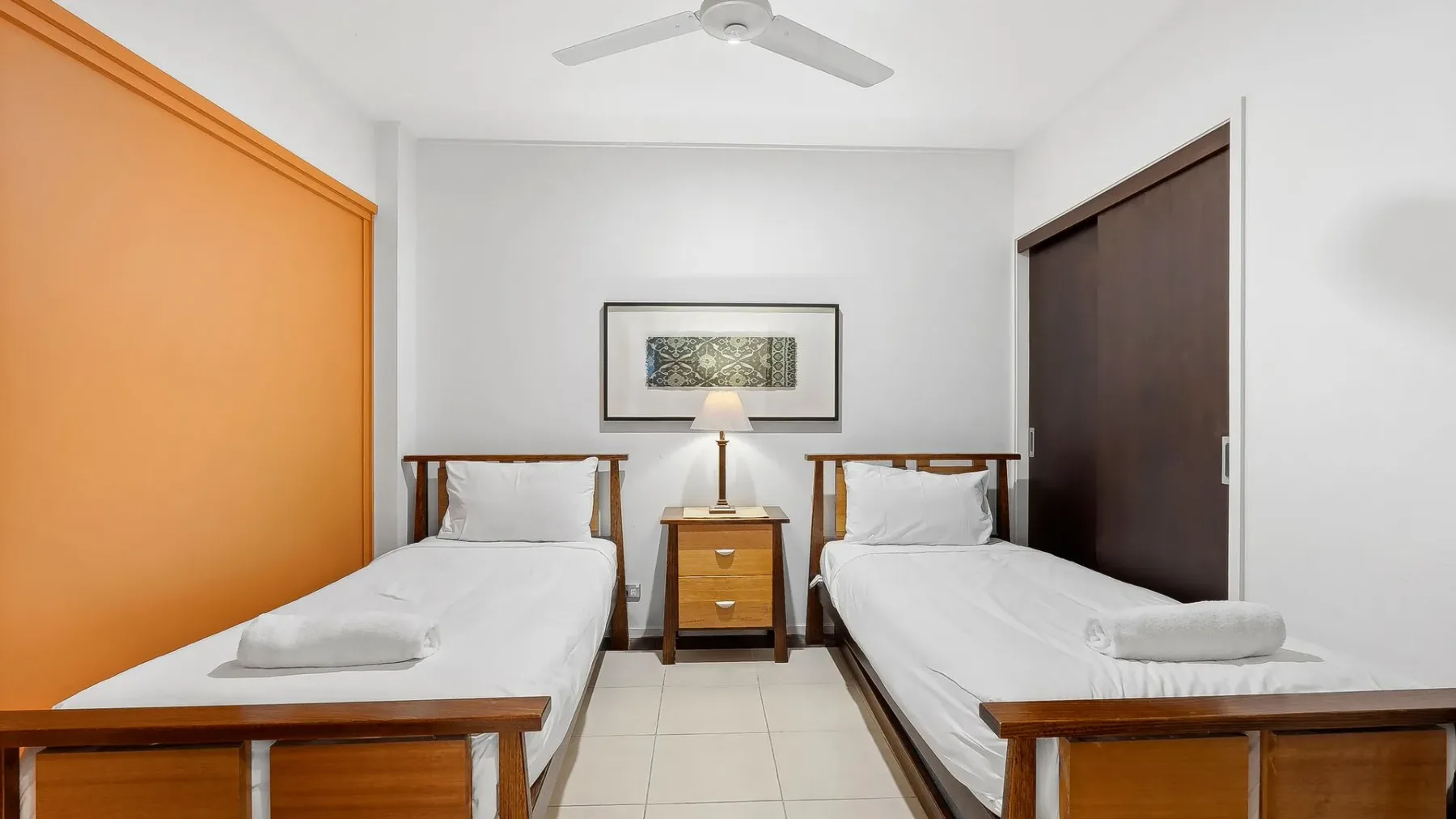 Un dormitorio con dos camas y una mesita de noche entre ellas.
