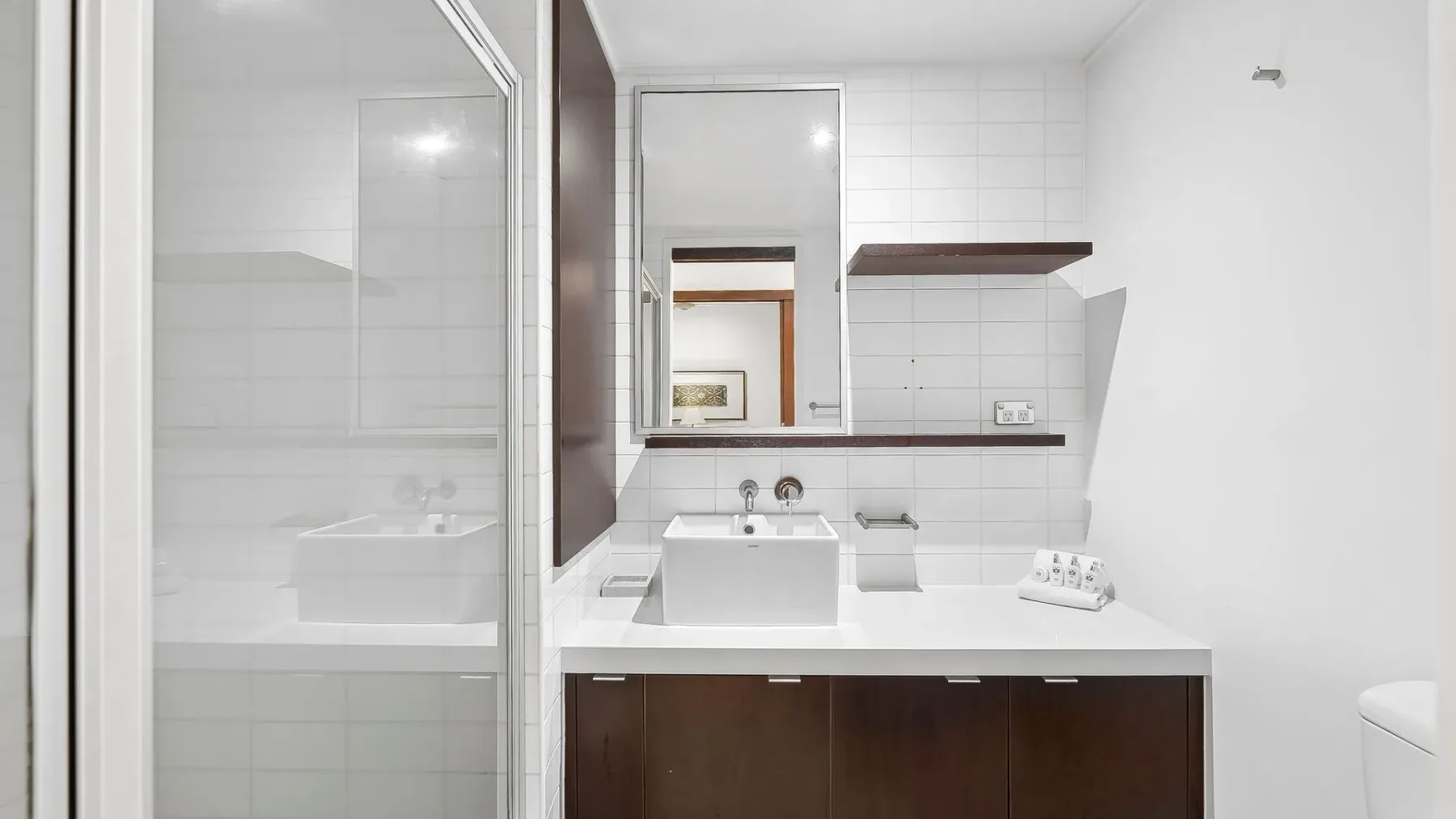 Un baño con azulejos, lavabo y ducha con mampara de vidrio.