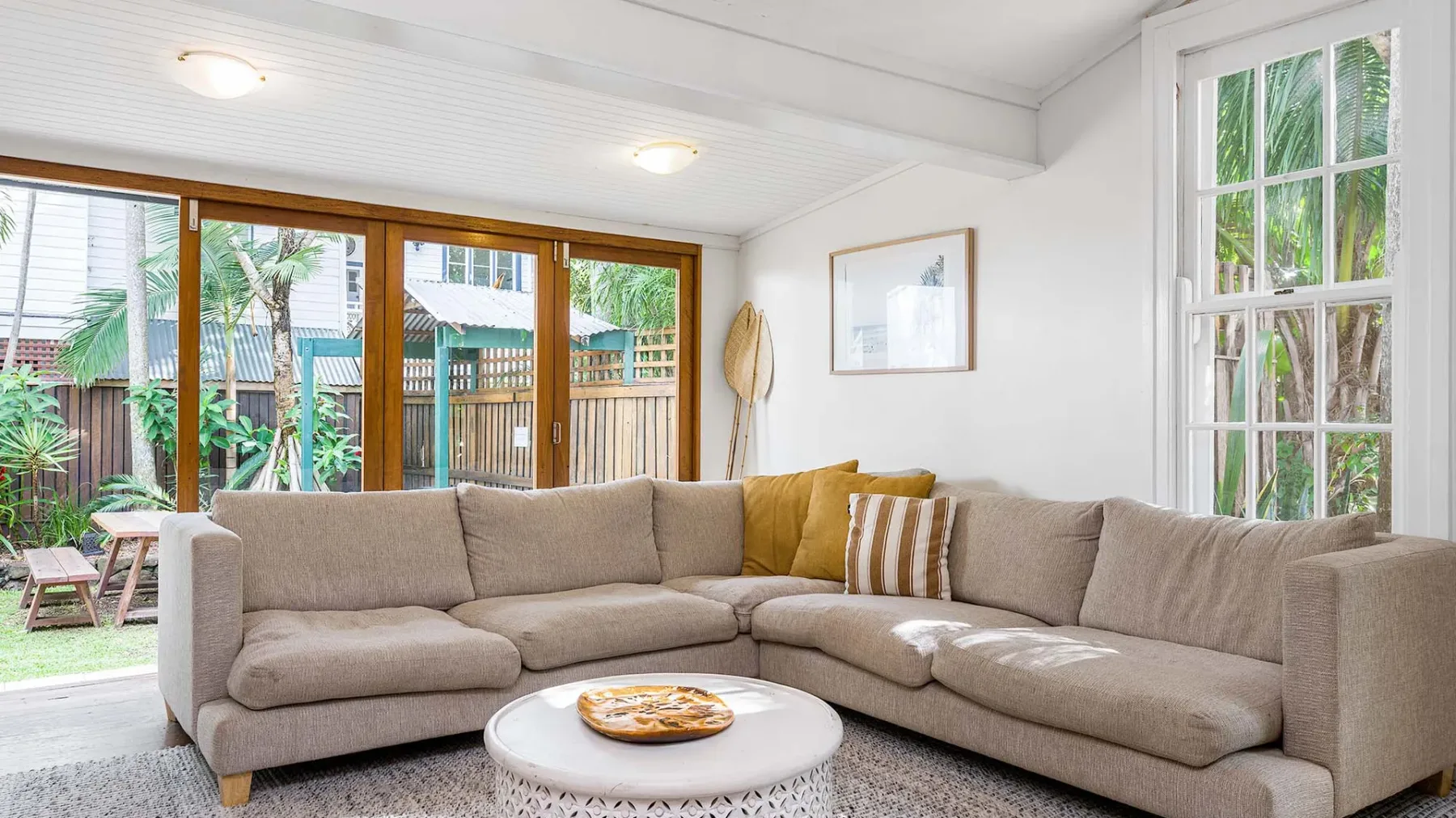Una sala luminosa con un sofá seccional junto a amplias ventanas y puertas corredizas de vidrio.