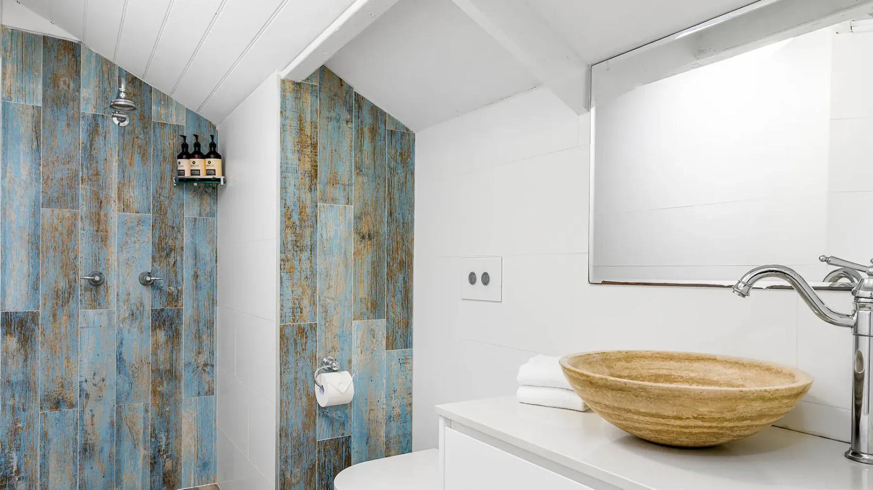 Un baño con ducha y un lavabo ancho en forma de cuenco sobre la encimera.