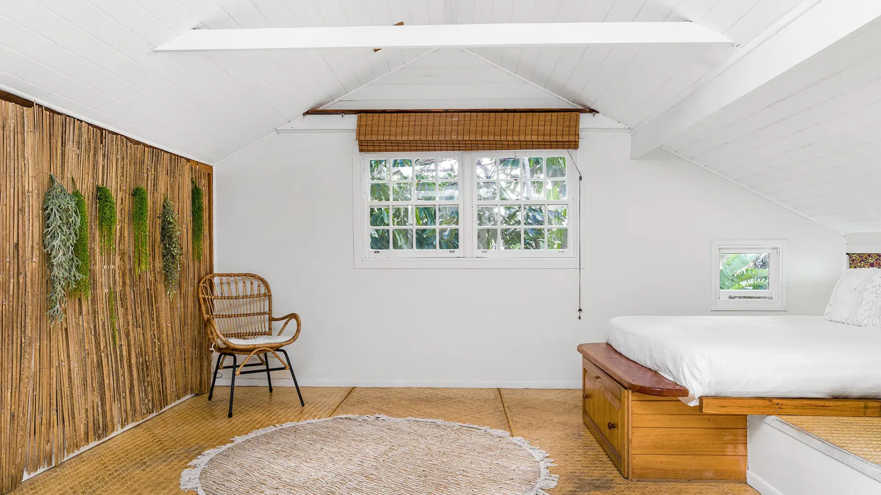Un dormitorio luminoso con una cama, una ventana y decoración tejida en la pared.