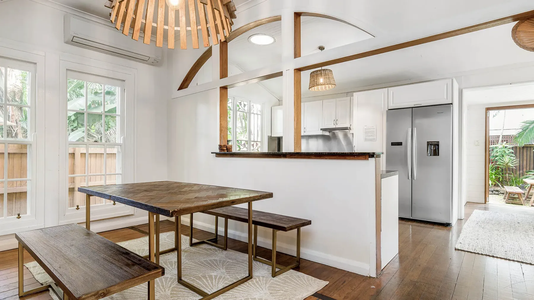 Una luminosa cocina y comedor de concepto abierto con una mesa larga de madera y bancos.