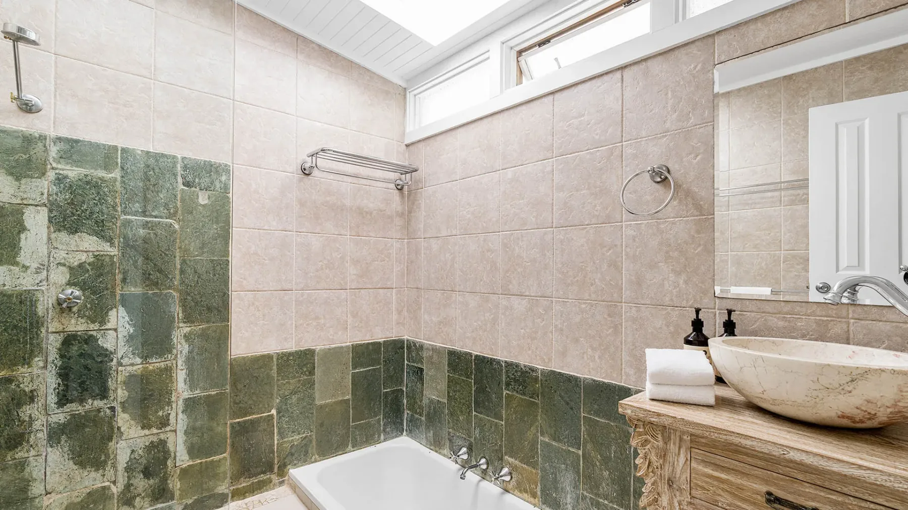 Un baño con azulejos, bañera, lavabo y ventanas altas.
