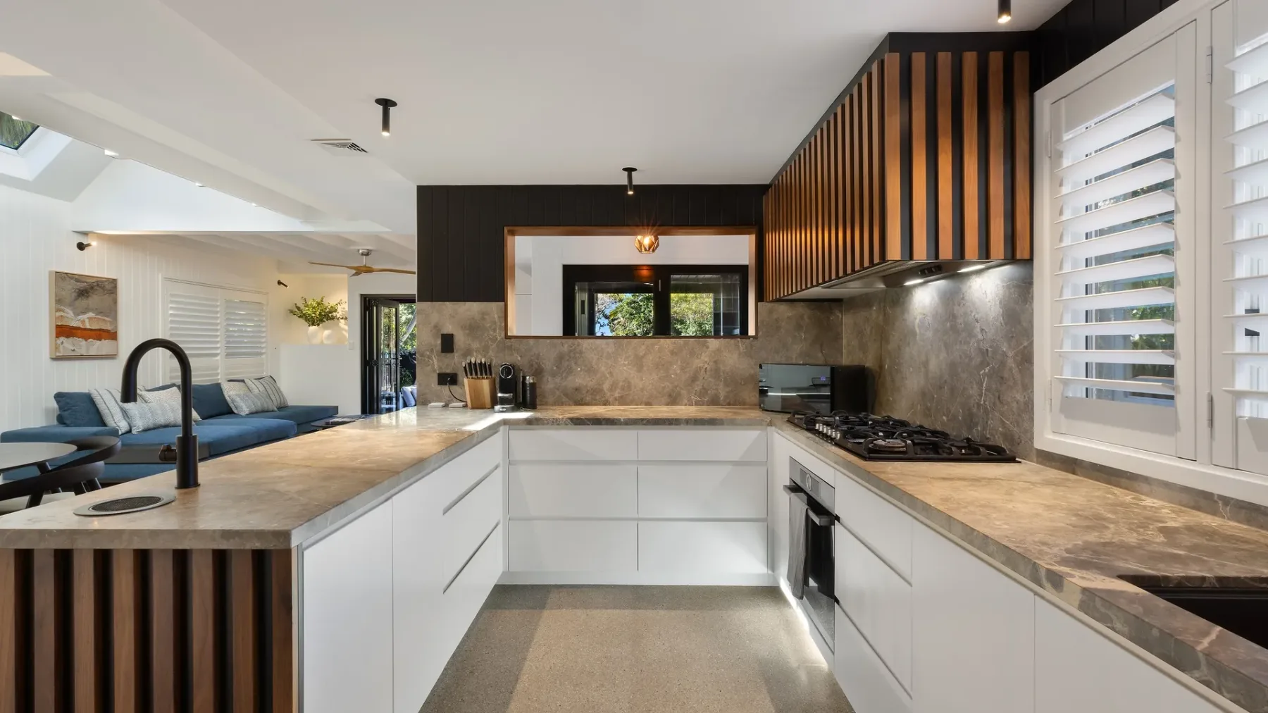 Una cocina moderna con gabinetes blancos y una larga encimera de piedra.