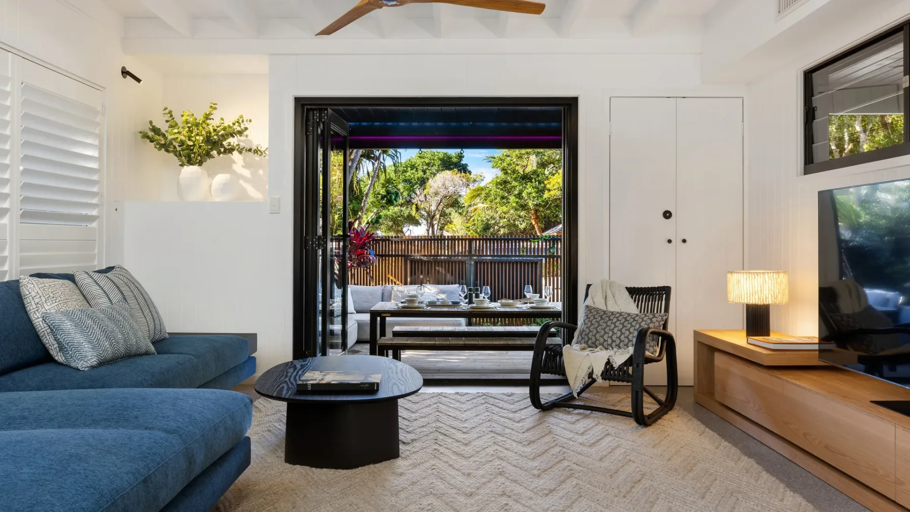 Una sala luminosa con asientos azules y una vista abierta a un patio frondoso.