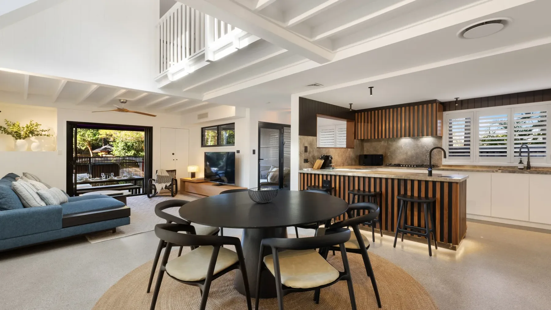 Una sala-comedor de planta abierta con una isla de cocina y ventanas grandes.