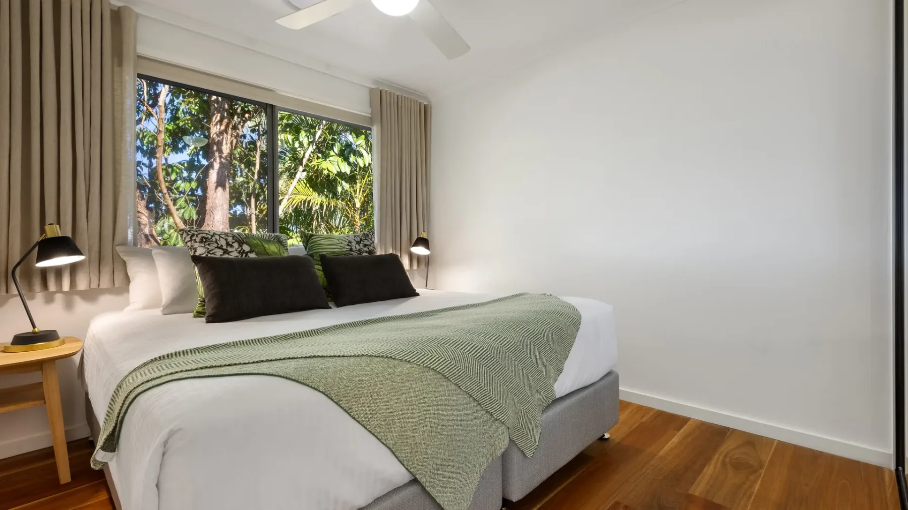 Un dormitorio con una cama bien tendida junto a una ventana grande.