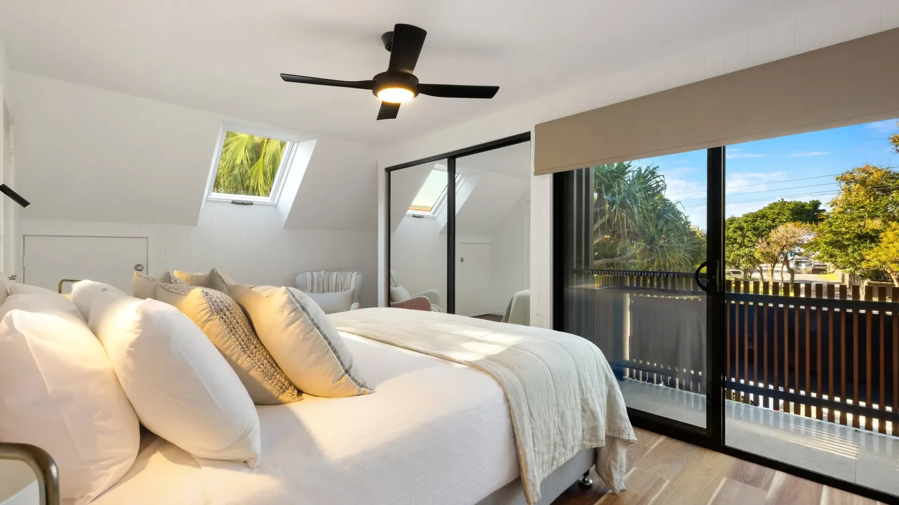 Un dormitorio luminoso con una cama junto a grandes puertas corredizas de vidrio.