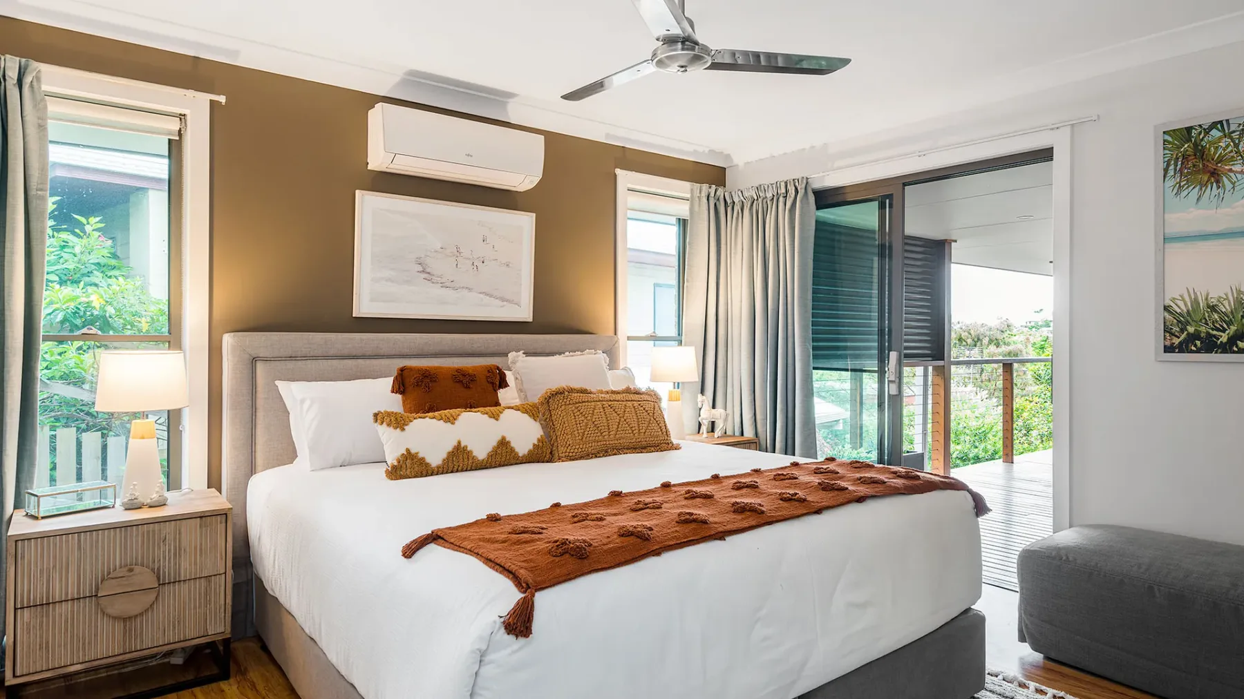 A bright bedroom with a large bed, bedside tables, and sliding glass doors.