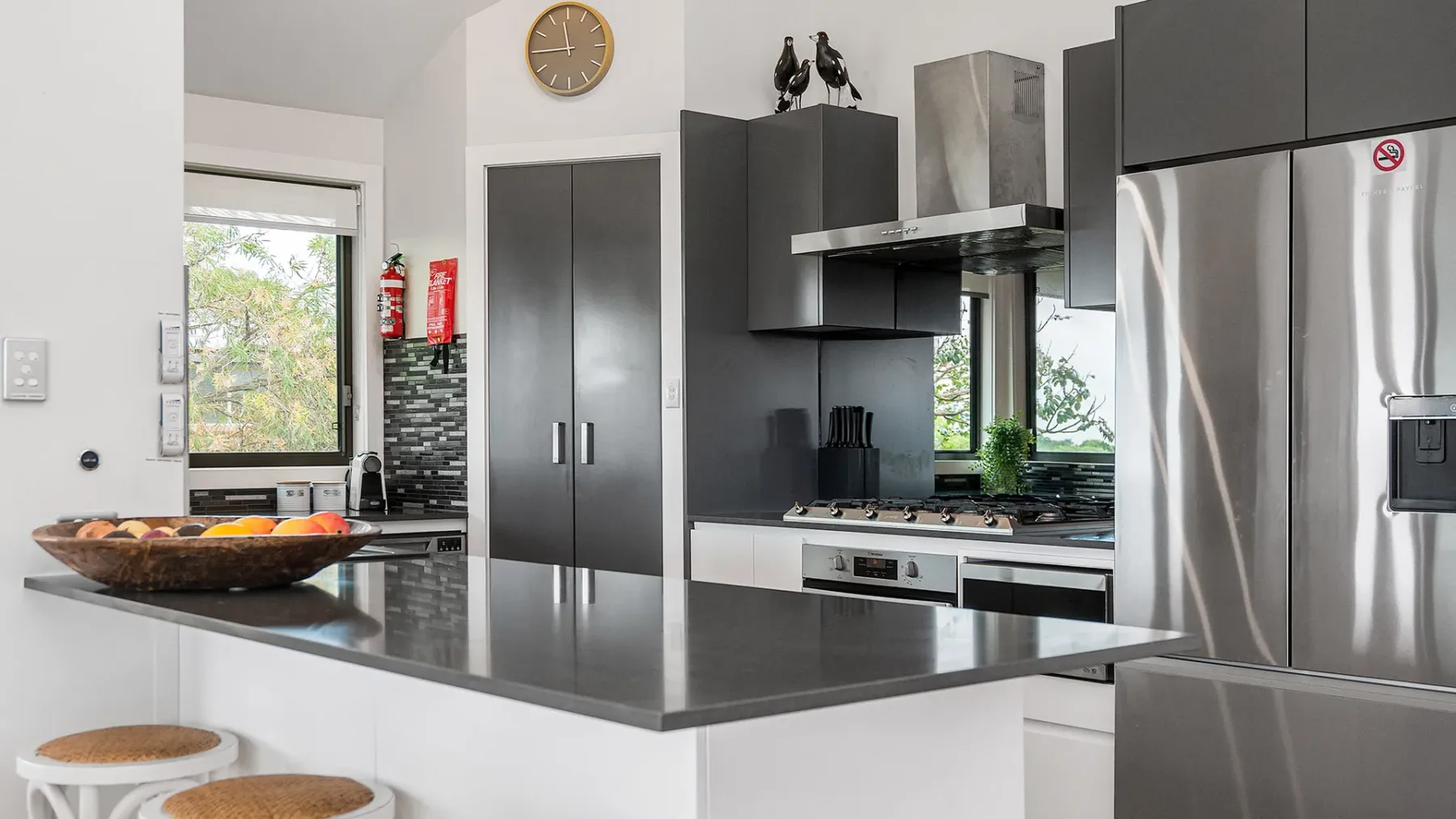 A modern kitchen with dark cabinets, stainless steel appliances, and a wide island.