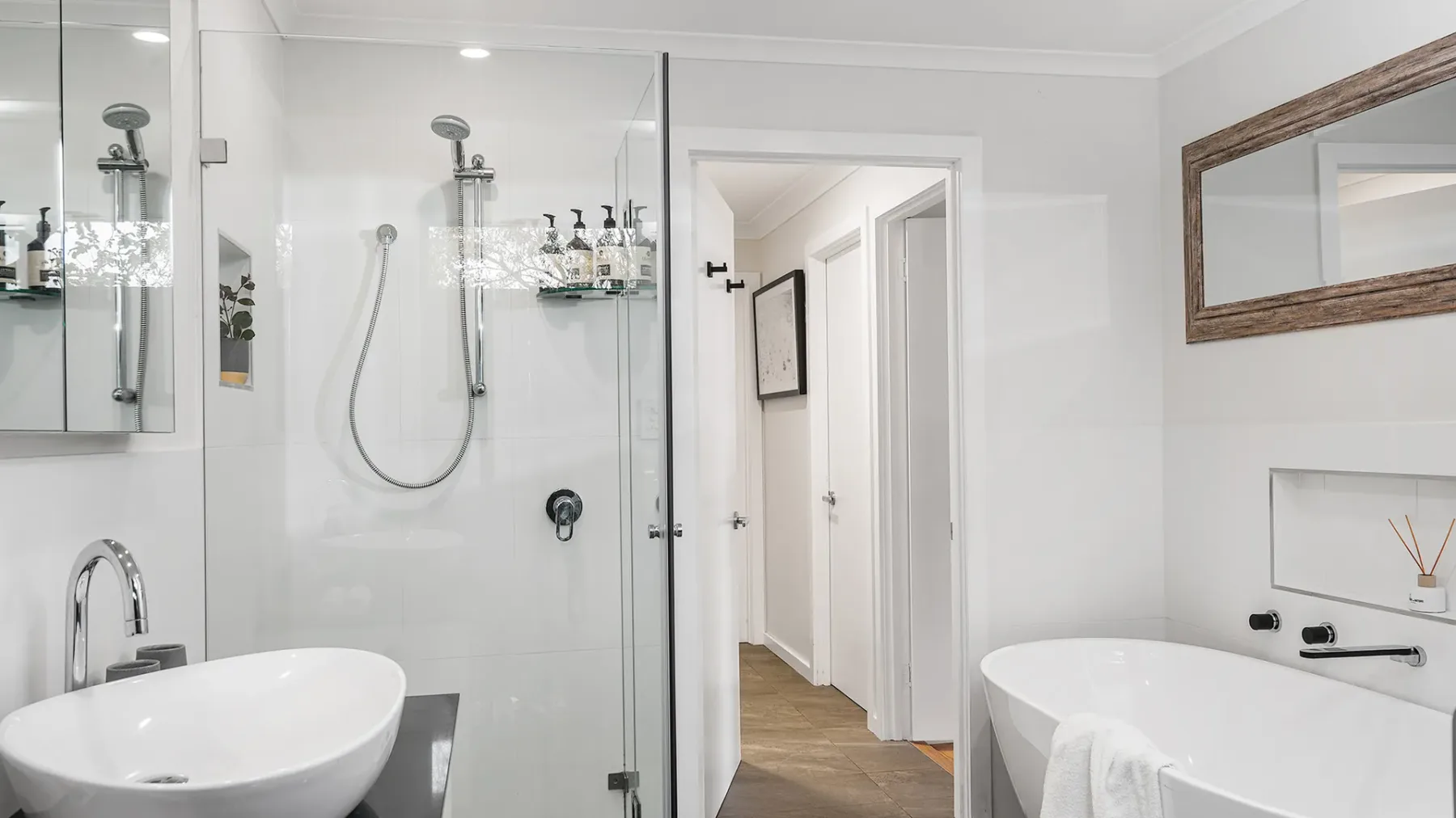 A bright bathroom with a glass shower, sink, and bathtub.