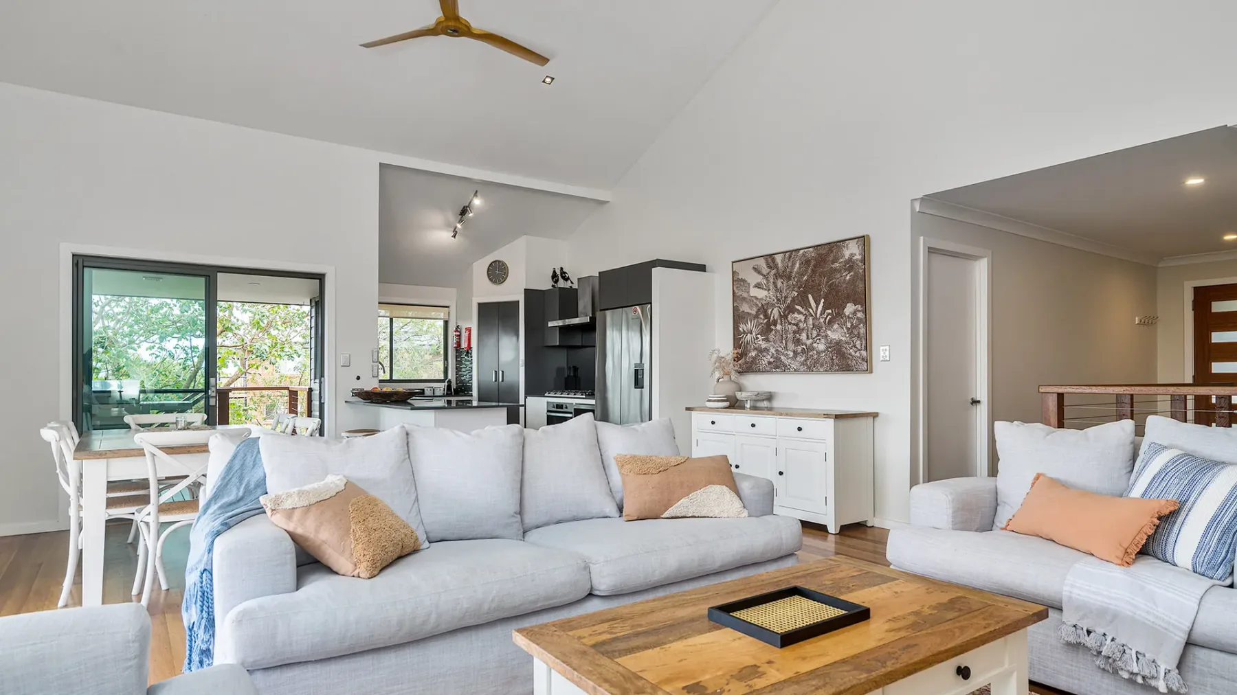 A bright living room with light-colored seating and a wooden coffee table.