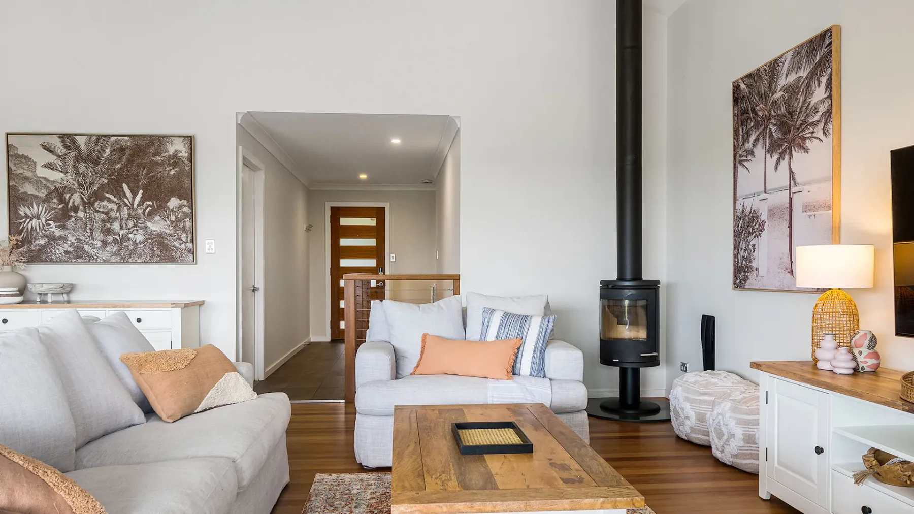 A bright living room with seating, a wooden coffee table, and a freestanding stove.