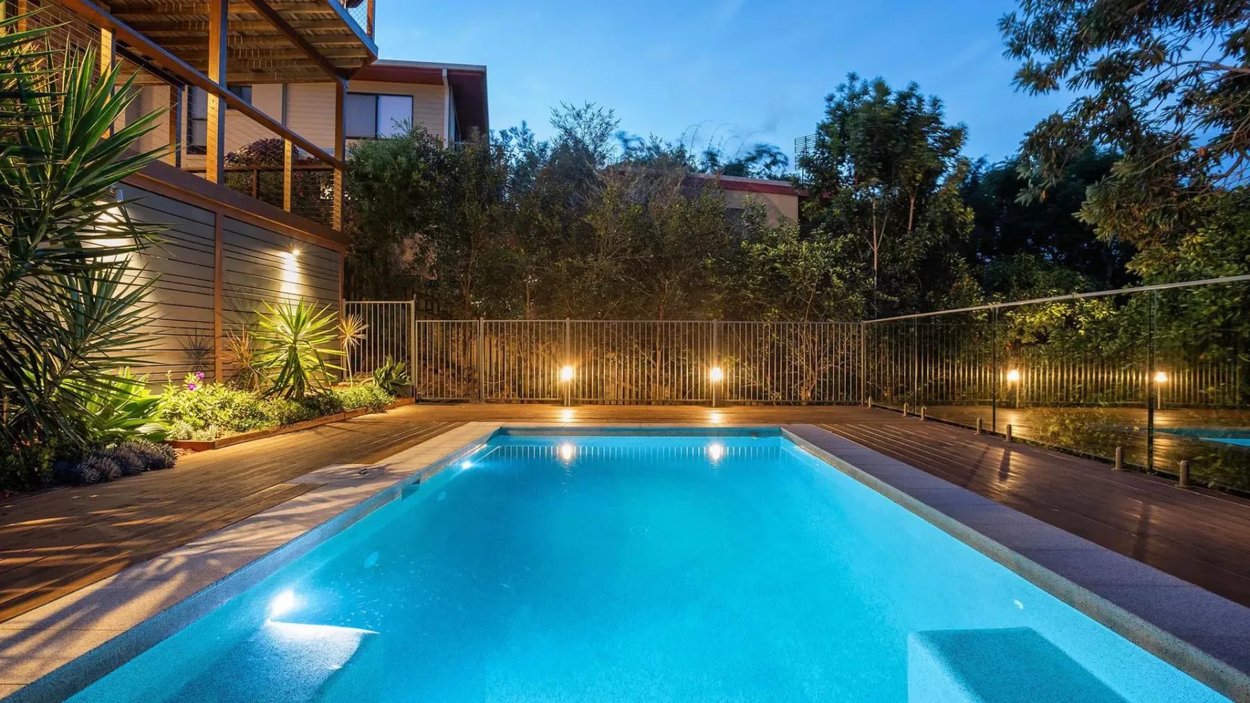 An outdoor swimming pool is surrounded by a wooden deck and trees.