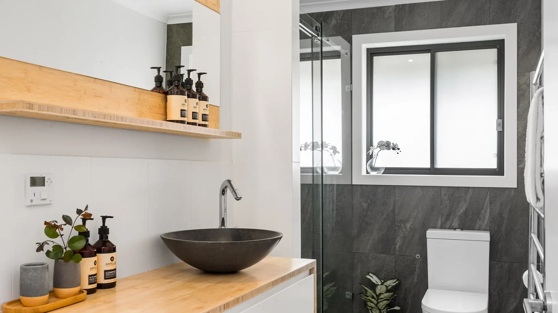 A bathroom with a vessel sink, toilet, and glass shower partition.
