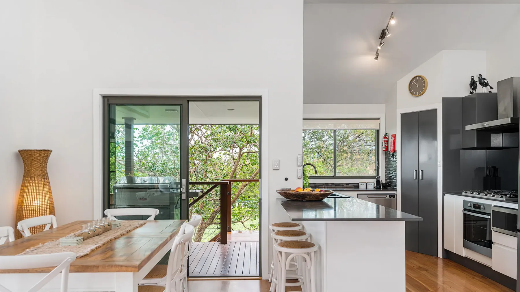 An open kitchen and dining area with a table beside glass doors opening onto a deck.