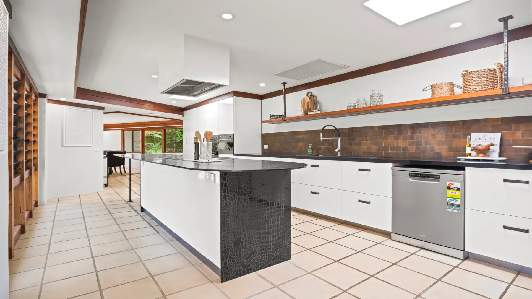 Una cocina luminosa con una isla larga y gabinetes blancos.