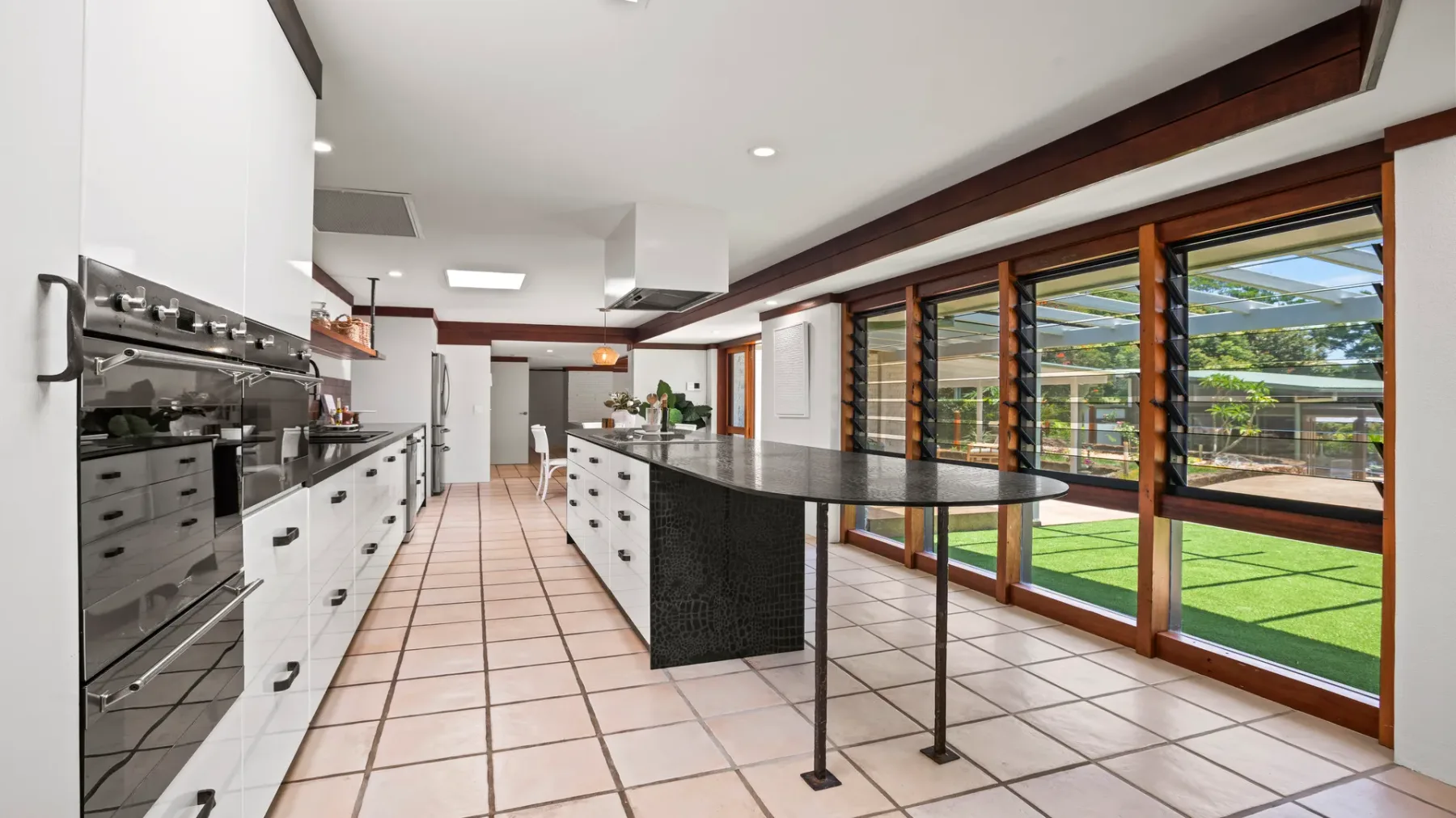 Una cocina amplia con una isla central y grandes ventanas con vista al césped.