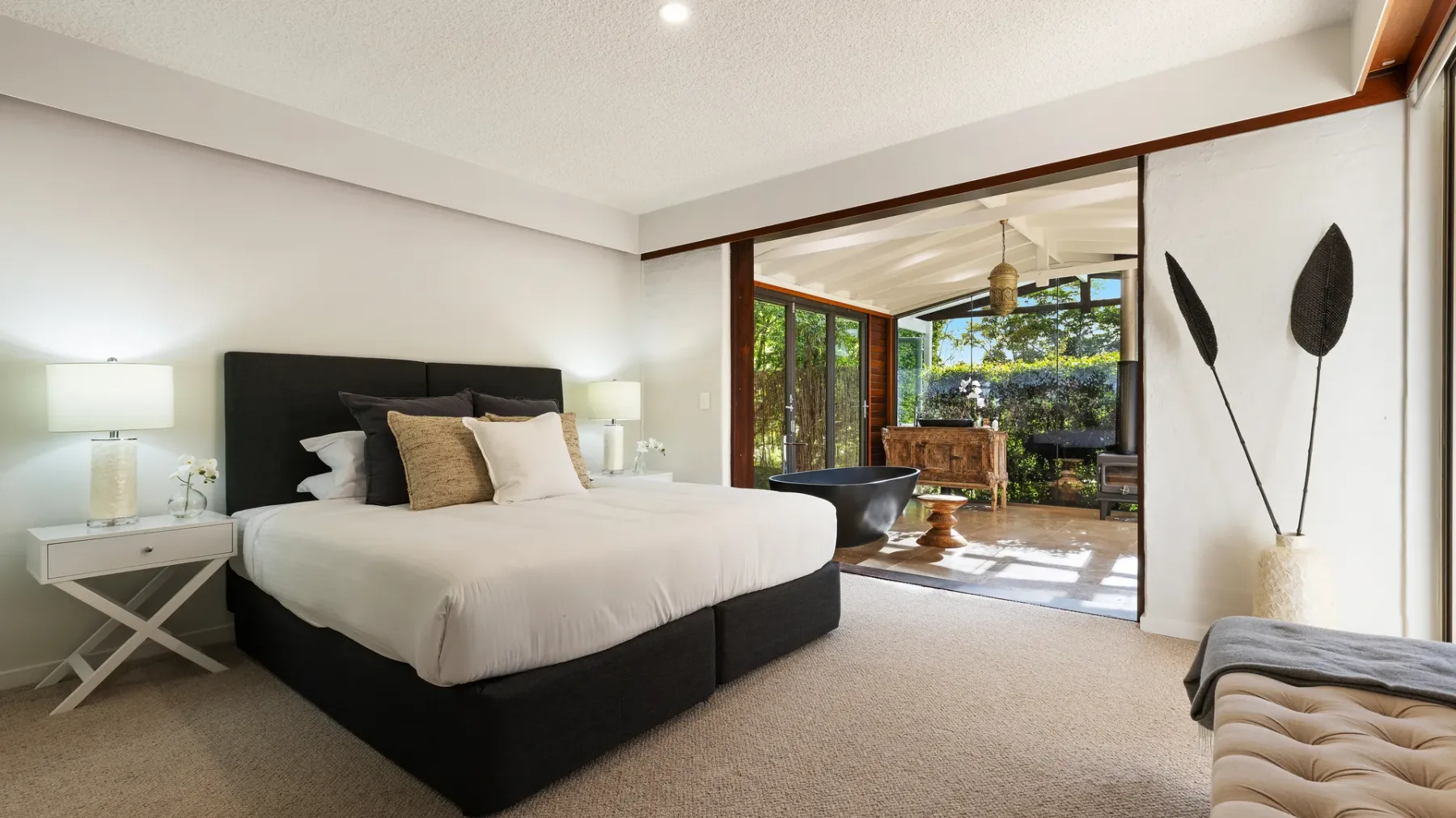 Un dormitorio con una cama grande y una zona de estar contigua y soleada.
