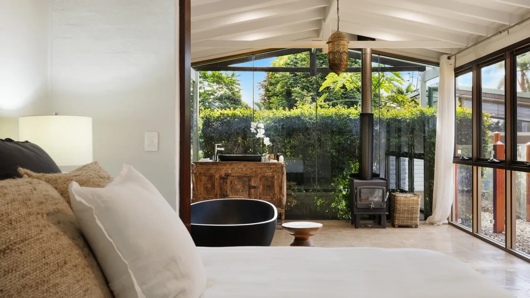 Un dormitorio luminoso da a una sala acristalada con vistas al jardín.