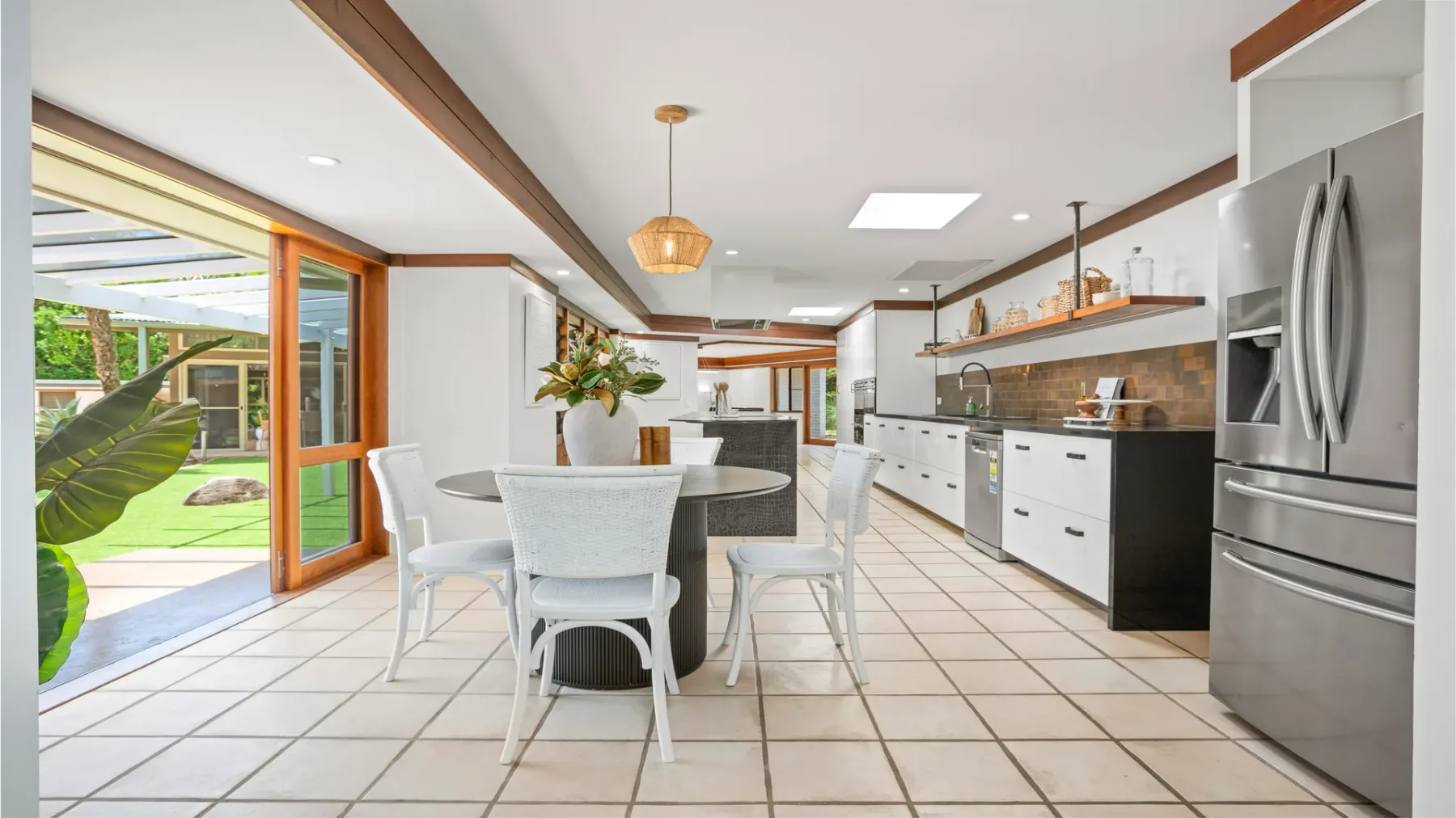 Una cocina y comedor luminosos con una encimera larga y puertas corredizas de vidrio.
