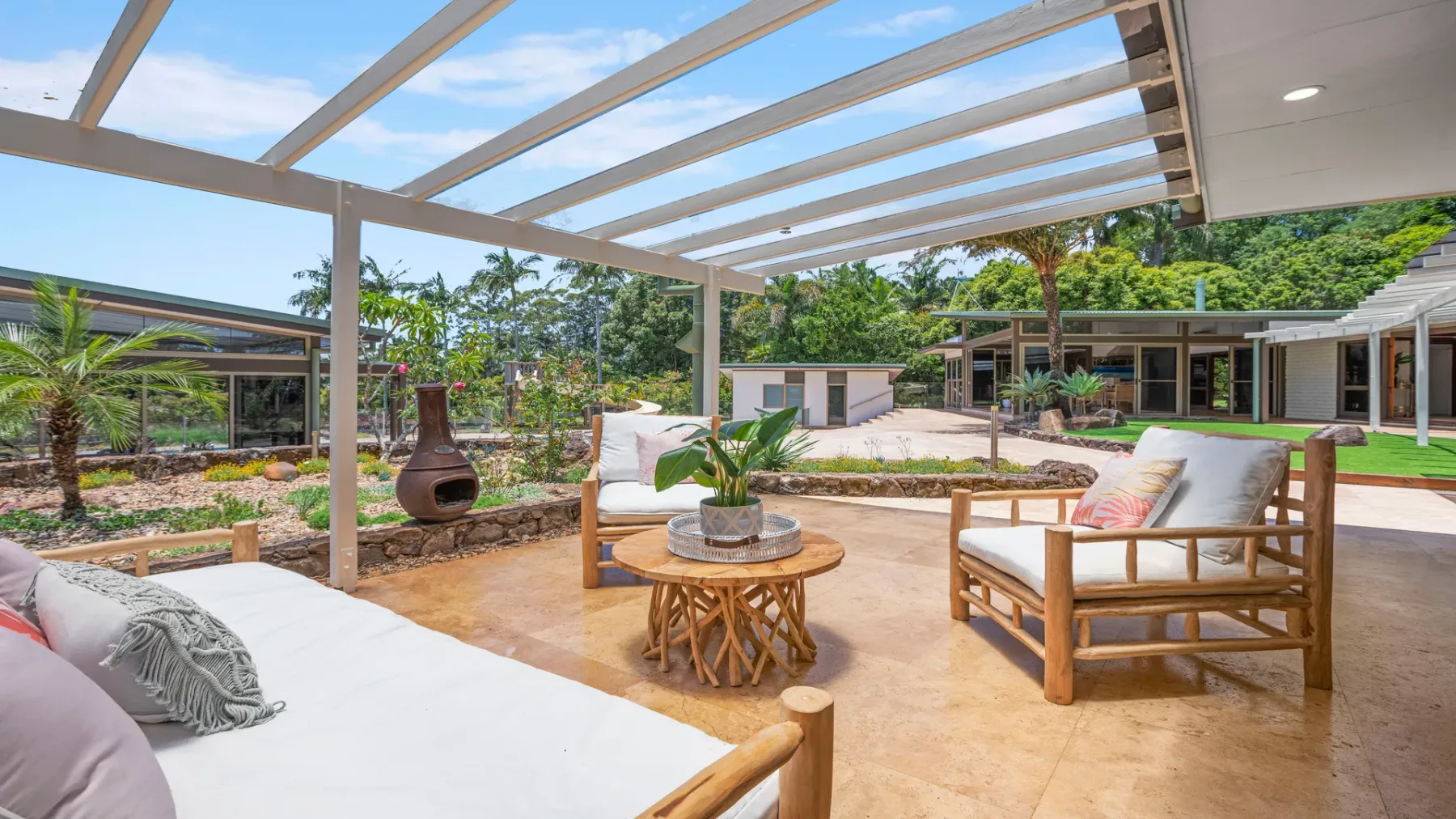 Una zona de estar exterior cubierta con una mesa baja de madera y vistas al jardín.