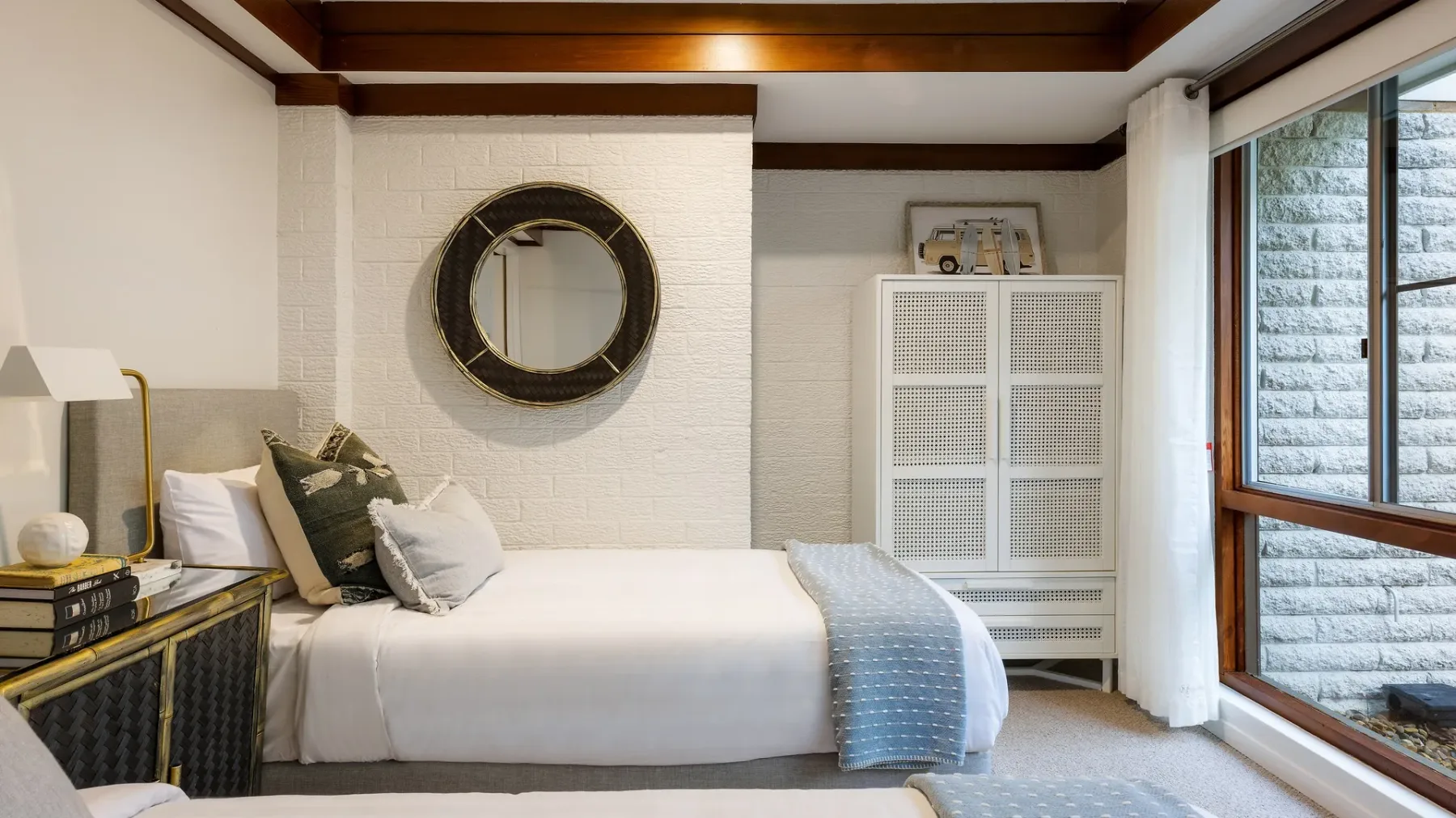 Un dormitorio con una cama bien tendida y una ventana grande.