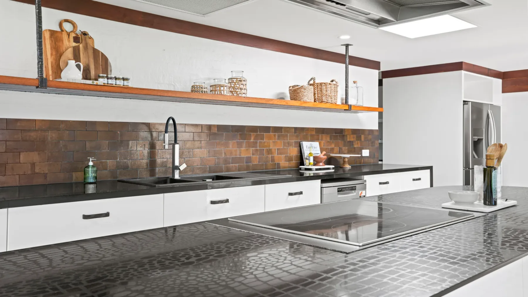 Una cocina moderna con armarios blancos, encimeras oscuras y una isla.
