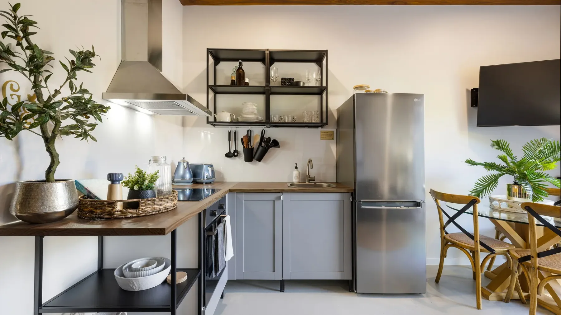 Una cocina con gabinetes grises, un refrigerador de acero inoxidable y una mesa de comedor.