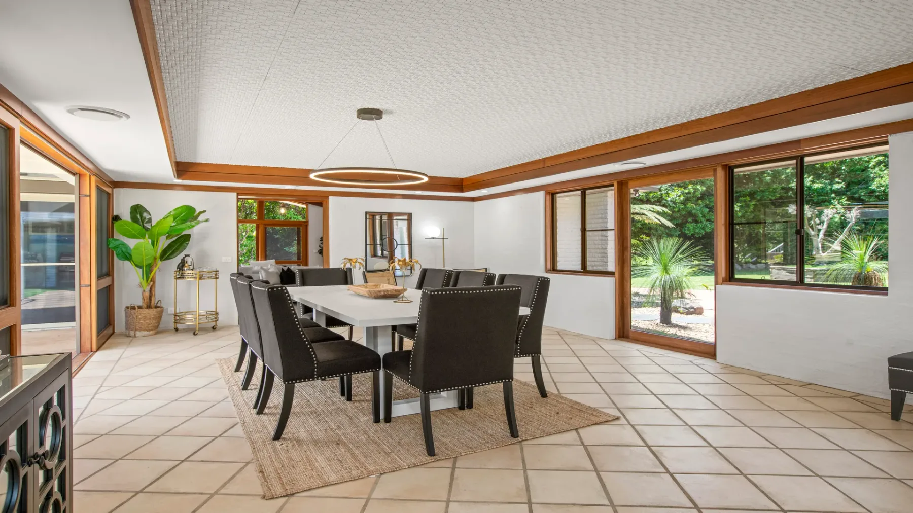 Un comedor luminoso con mesa y asientos junto a grandes ventanales.