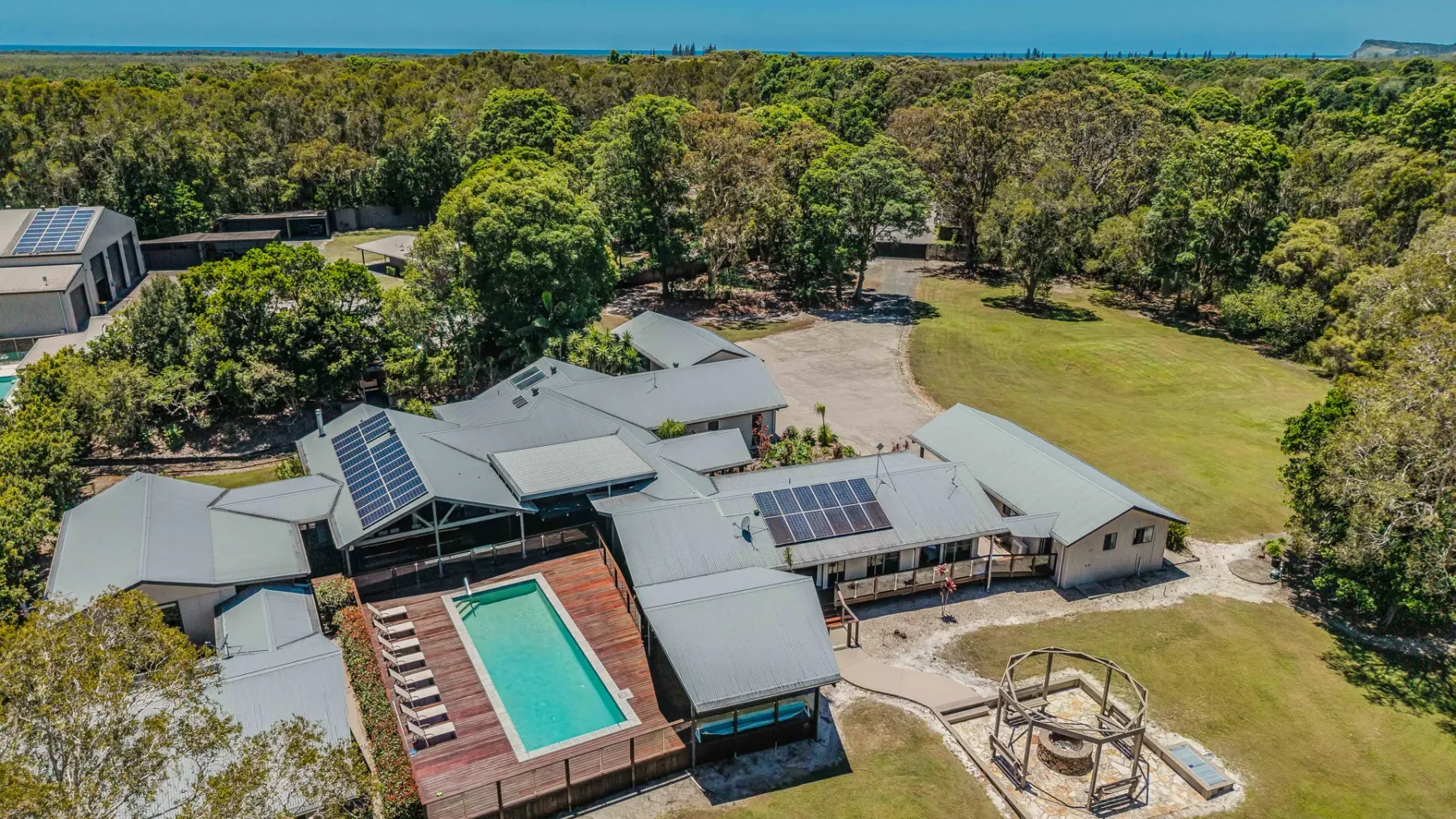 An aerial view shows a large building, a swimming pool, and open grassy grounds.